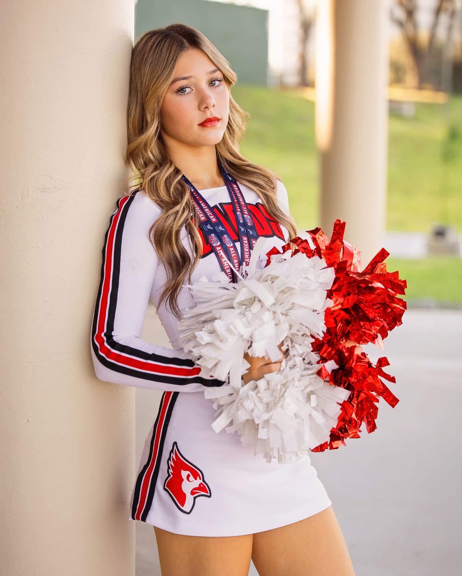 Athletic uniform with red and white pom poms photographed in front of architectural columns.