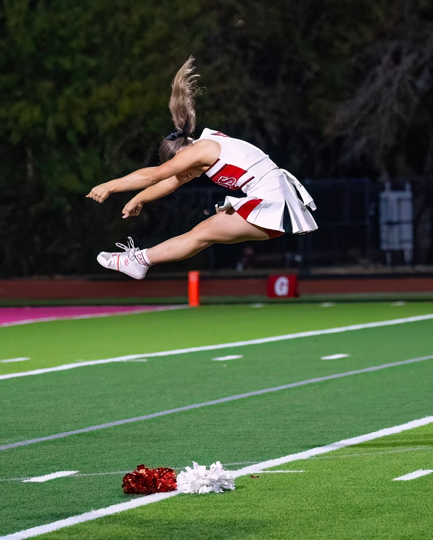 Performer executes an impressive aerial jump on the football field during a routine.