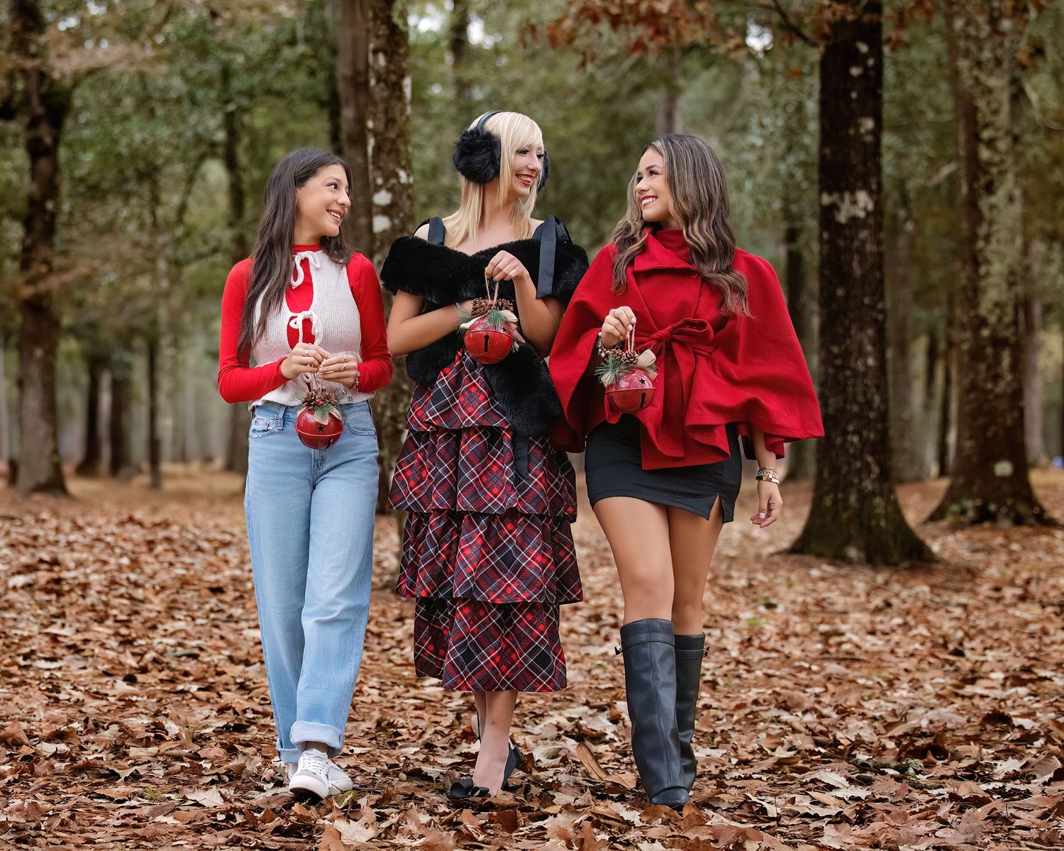 Friend photoshoot with Seniors walking together through a fall forest covered in brown leaves.