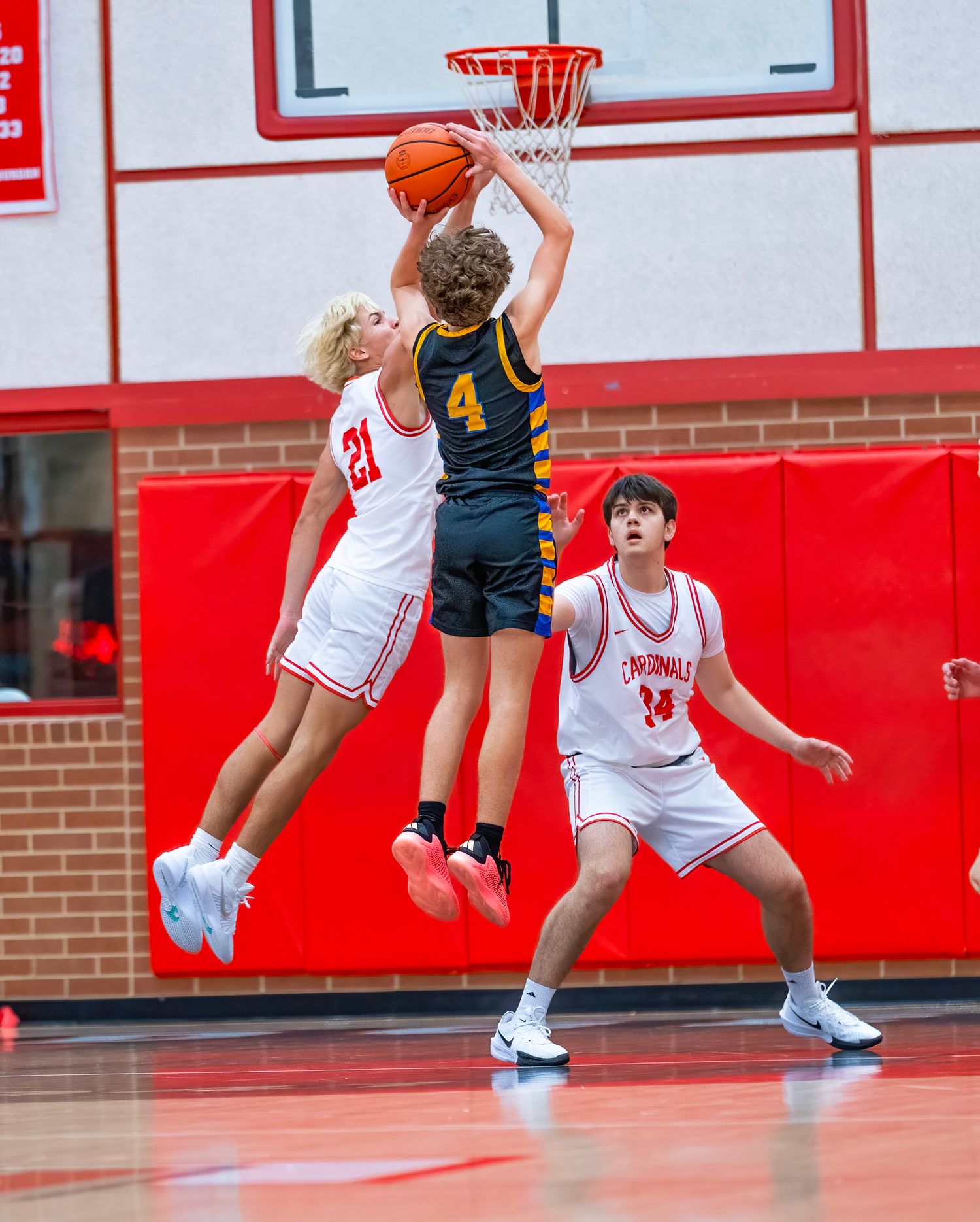 Game Day Basketball players compete for possession during an intense game on a red and white court.