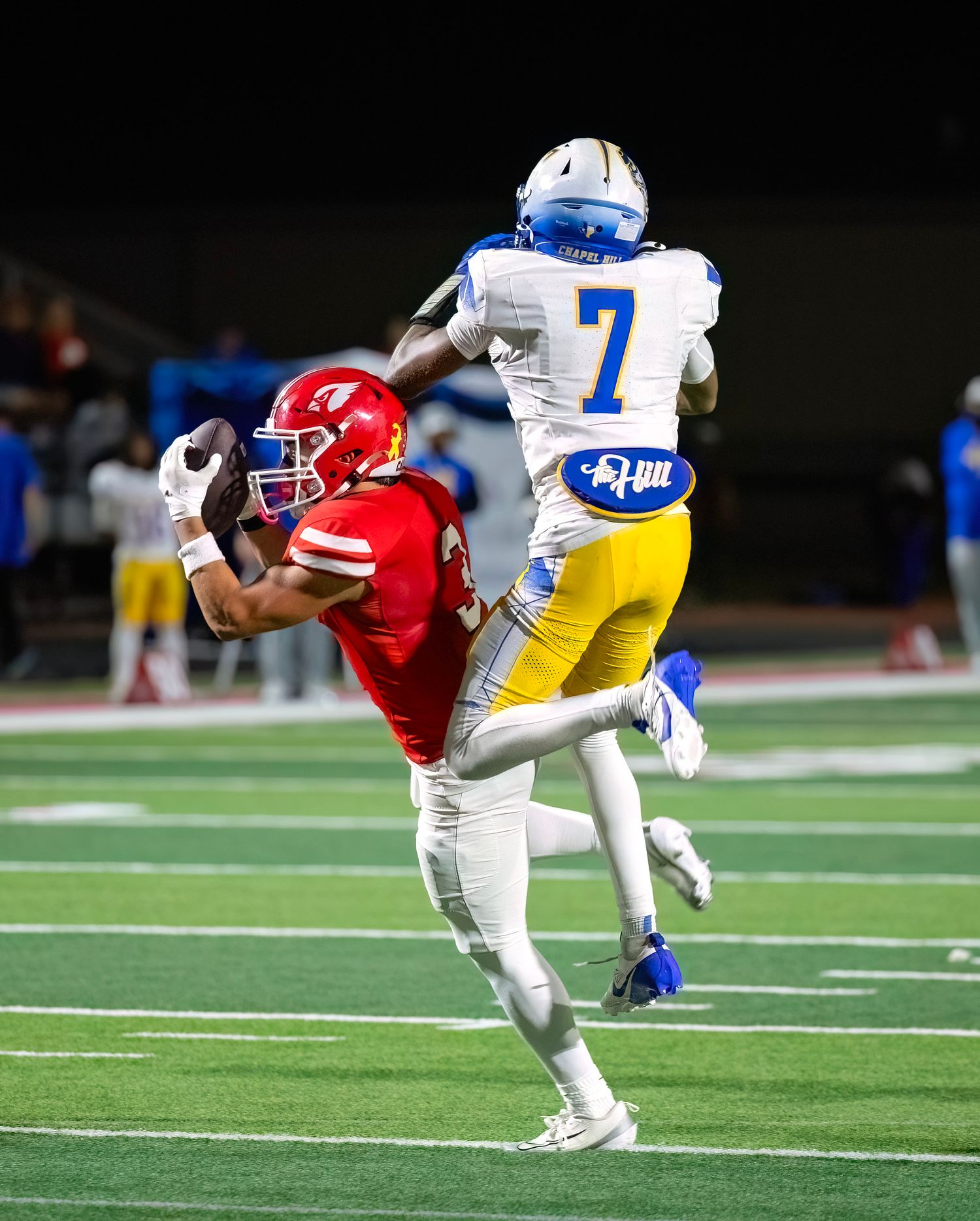 Football players from opposing teams collide during an intense tackle on the field.