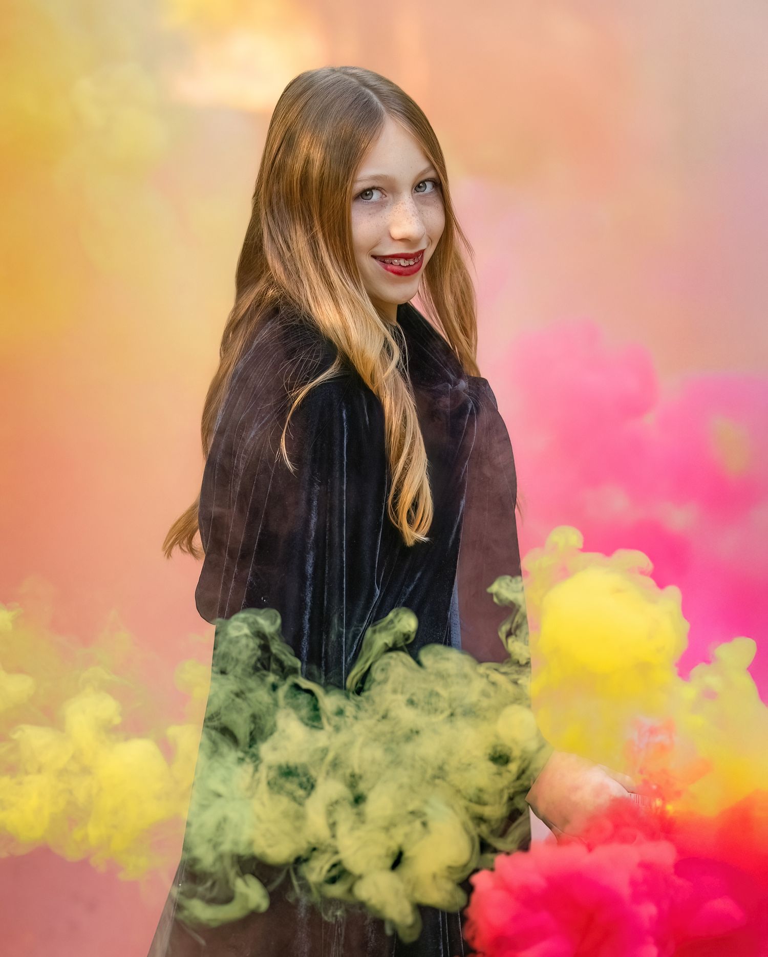 A creative portrait with colorful smoke bombs creating yellow, pink and green effects.