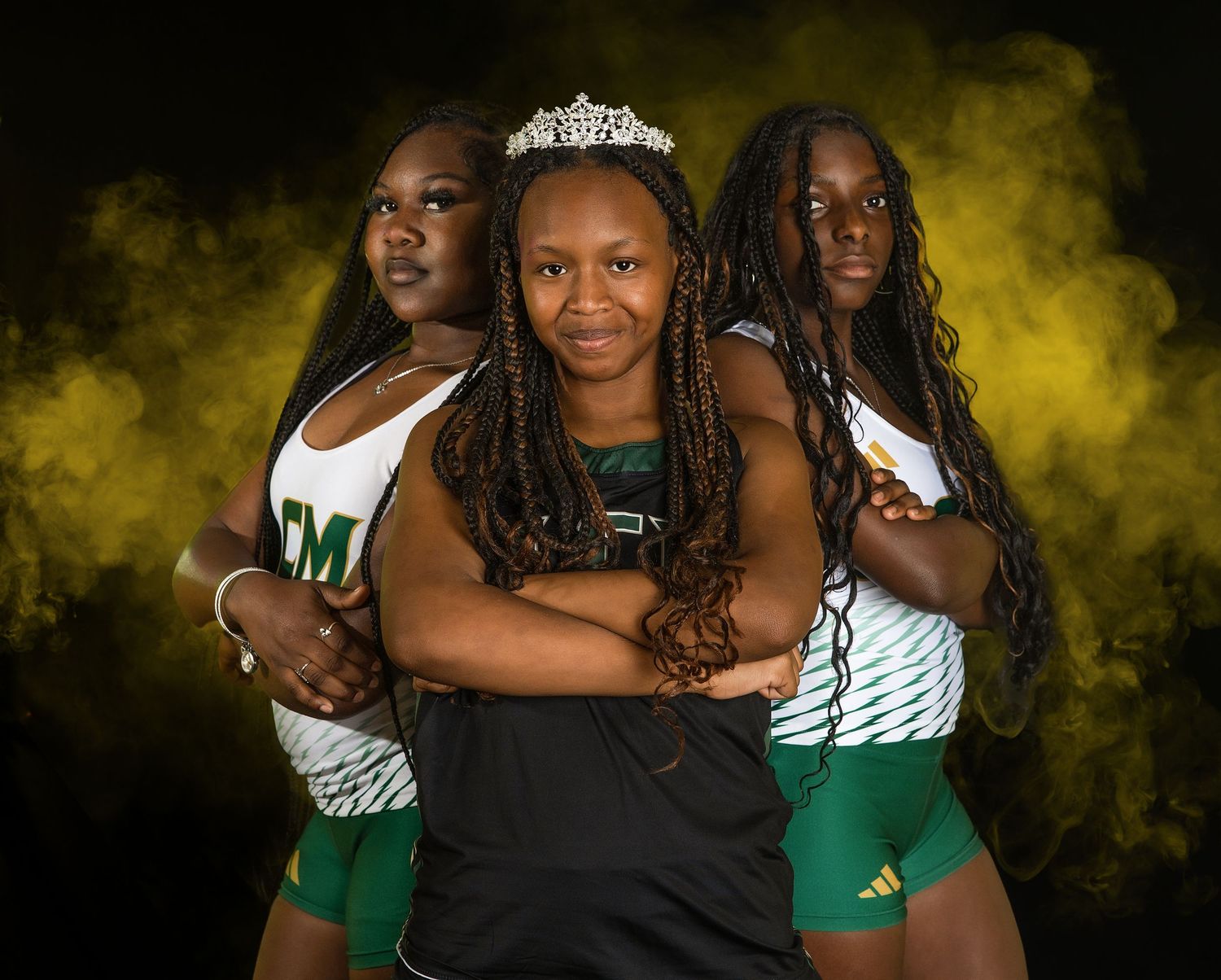 A group poses together in black and green outfits against a dramatic yellow-lit backdrop for formal photos.