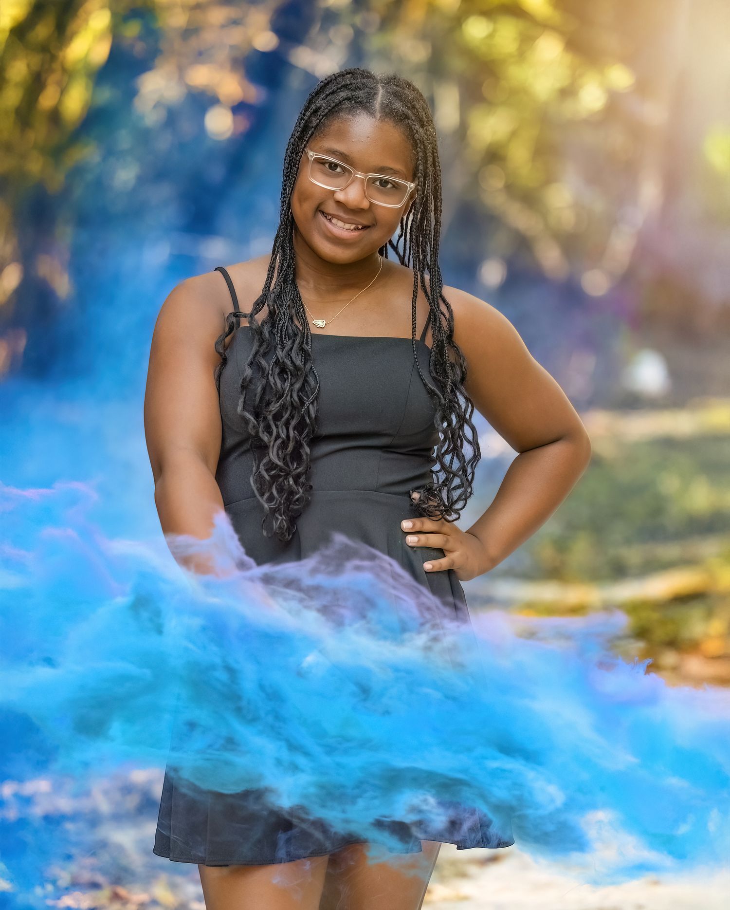 Creative portrait session with blue smoke effects in a natural outdoor setting.