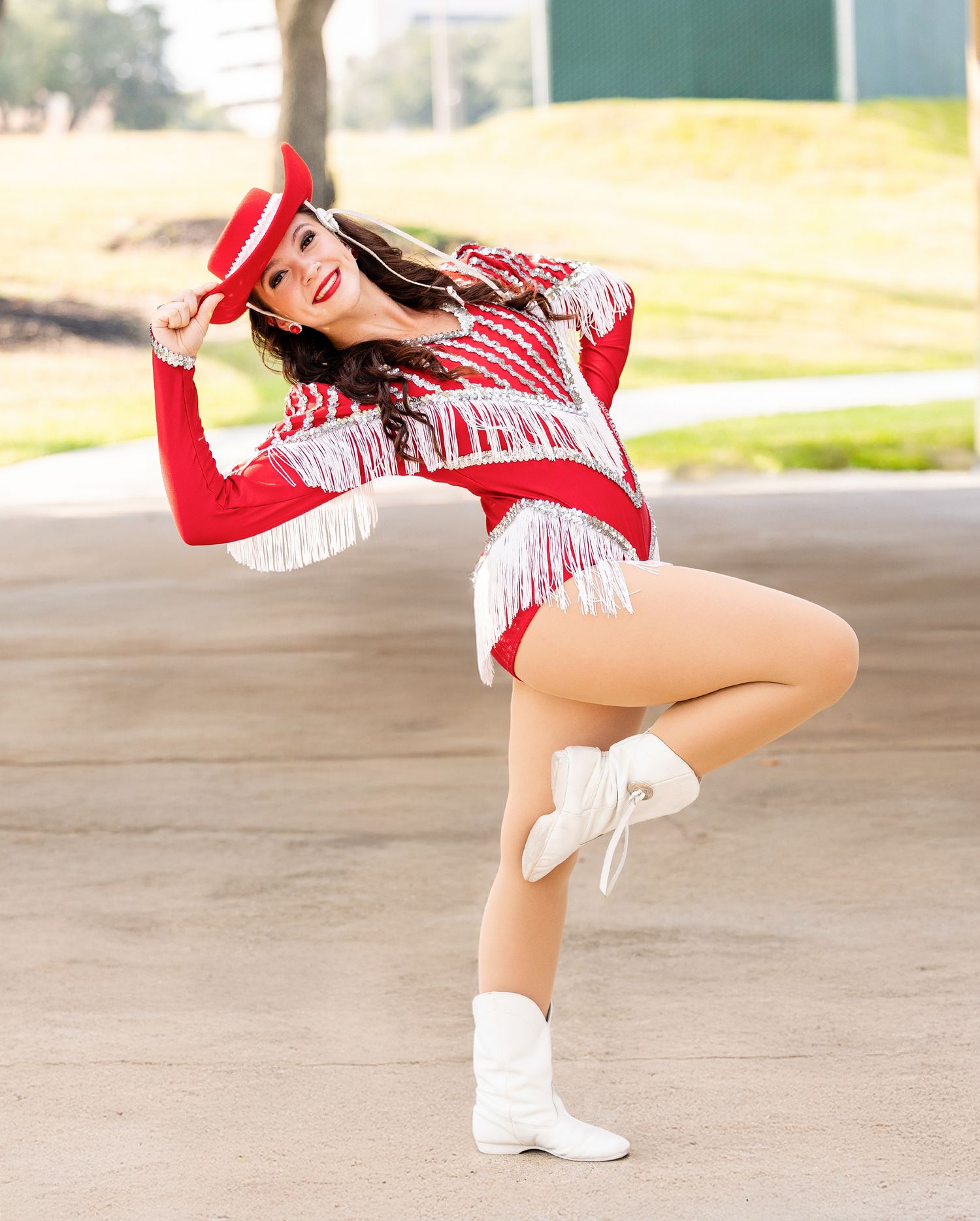 A dancer in a red and white uniform strikes a dynamic pose while performing outdoors.