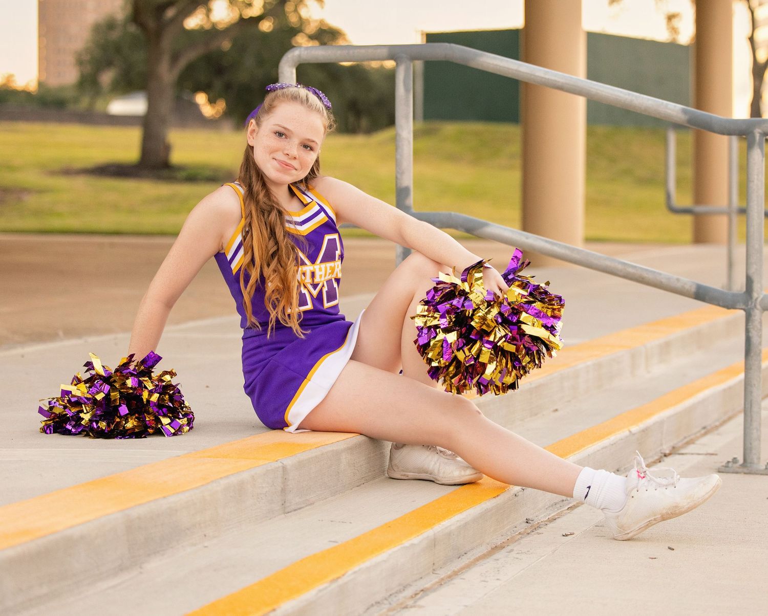 Purple and black cheerleading uniform with pom poms shown in segments on concrete steps.