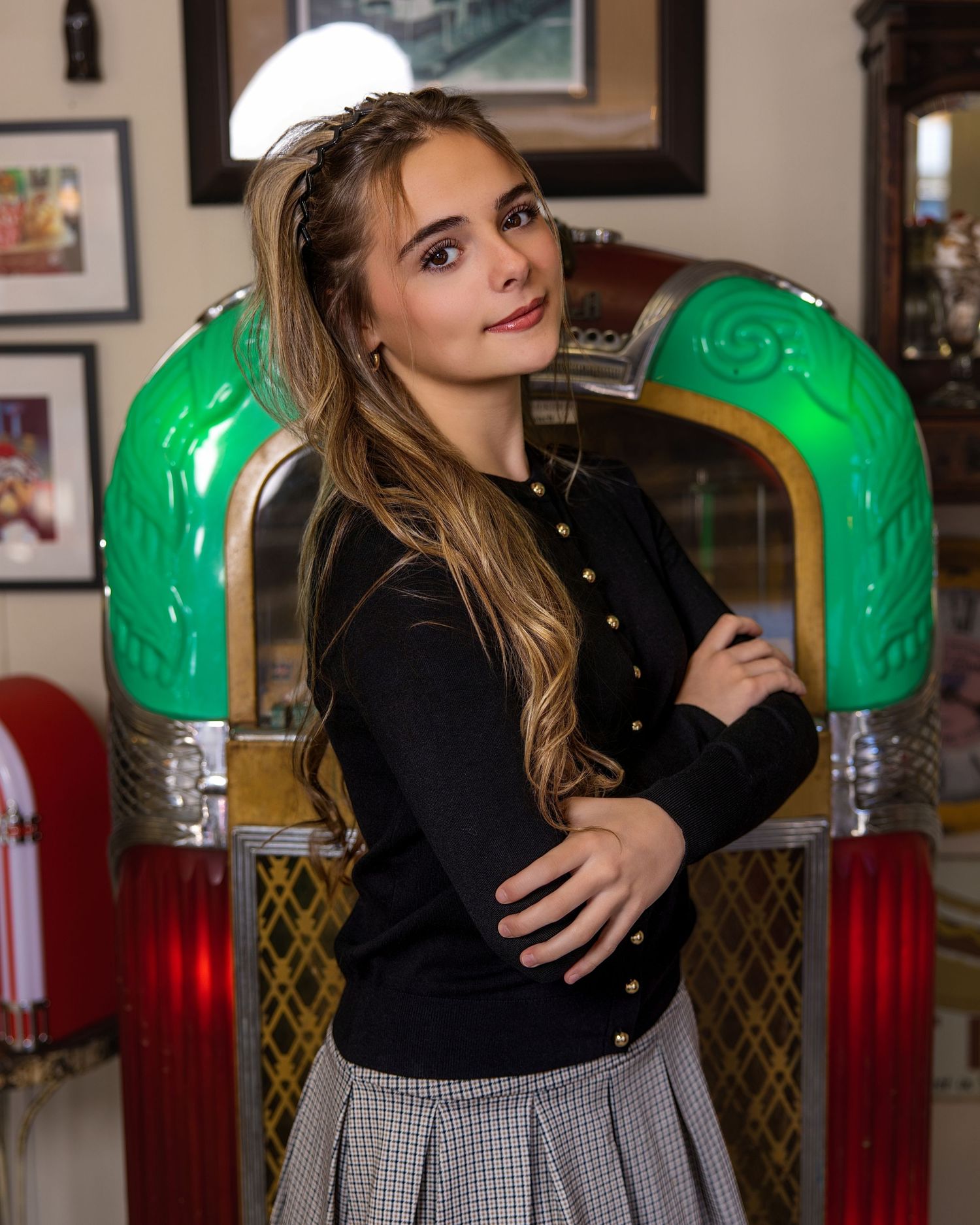 Indoor photo series showing someone in black and checkered outfit posing near green vintage lamps.