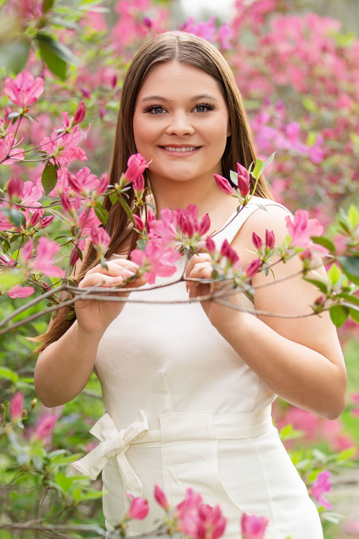 Isn't she beautiful in her white dress posing among blooming pink azalea flowers in a garden setting. BCHS Senior