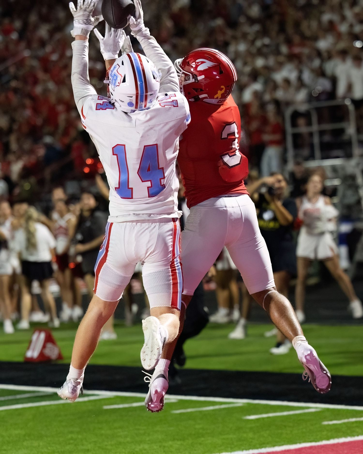 Football players leaping to make a play during an intense game moment.