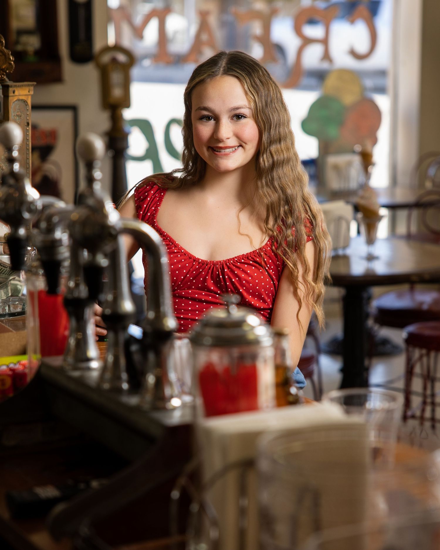 A series of photos in a vintage diner setting featuring someone in a red polka dot dress.