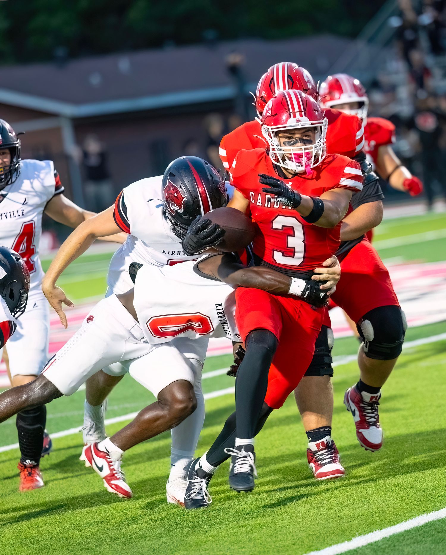 Abraham Munguia,  in red jersey number 3 breaks through defensive tackle attempt during intense game action on field.
