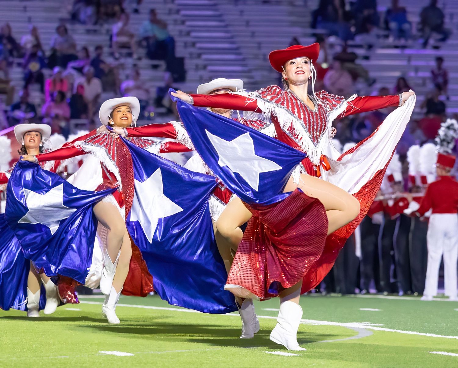 Cheerleaders performing synchronized acrobatic routines in red, white and blue uniforms.