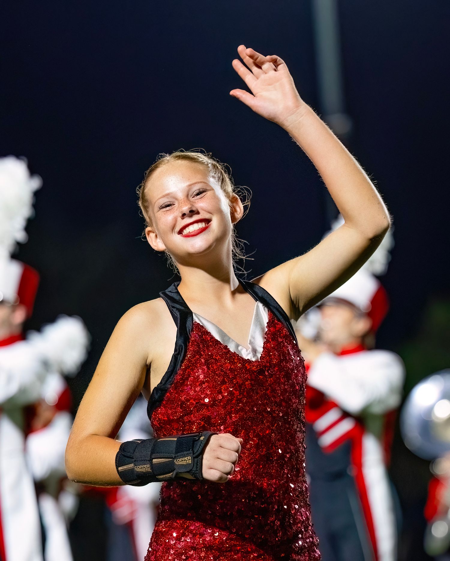 Performer in sparkly red costume dances during halftime show at night.
