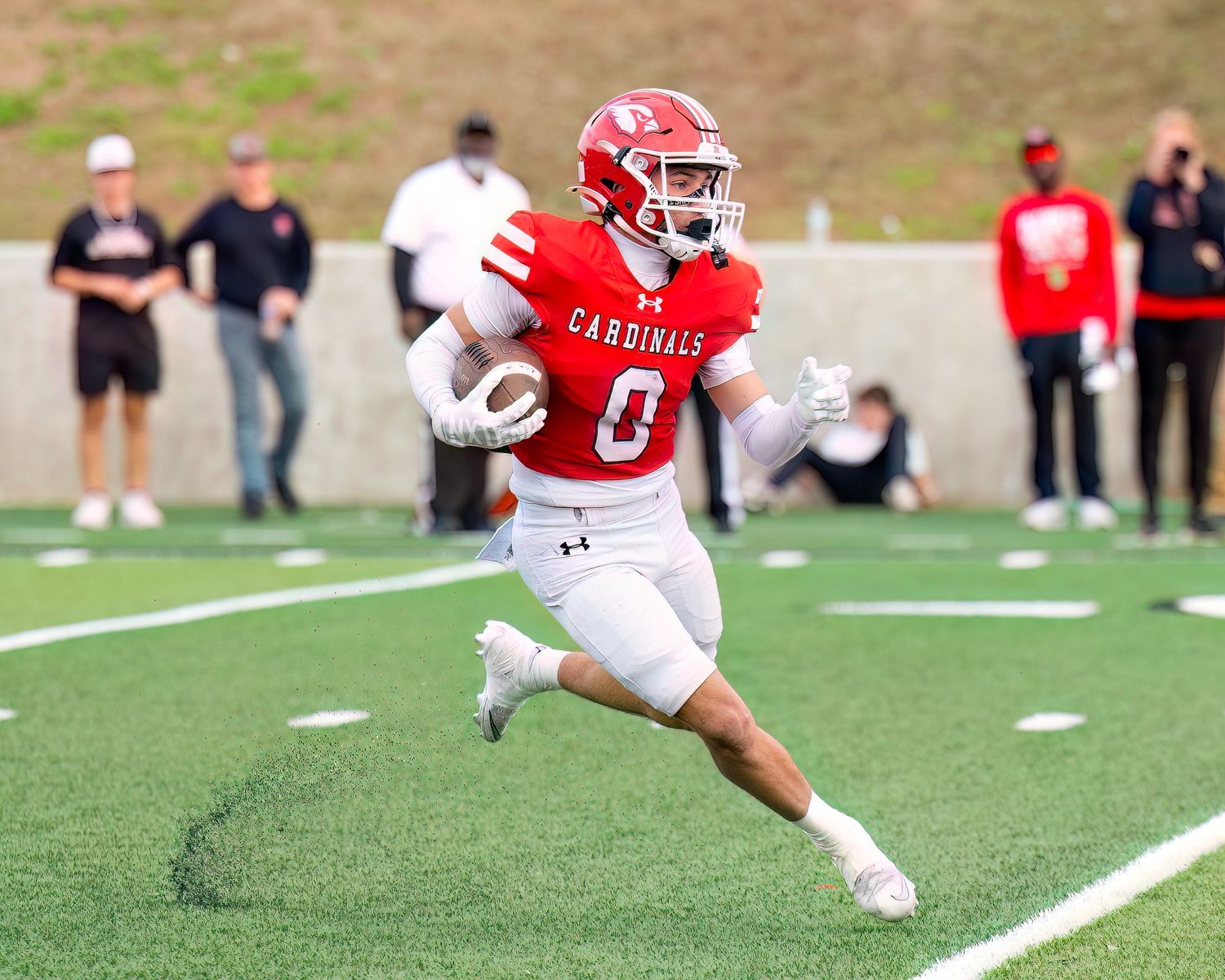 Bridge City High School Football player in red and white uniform running with the ball on the field.