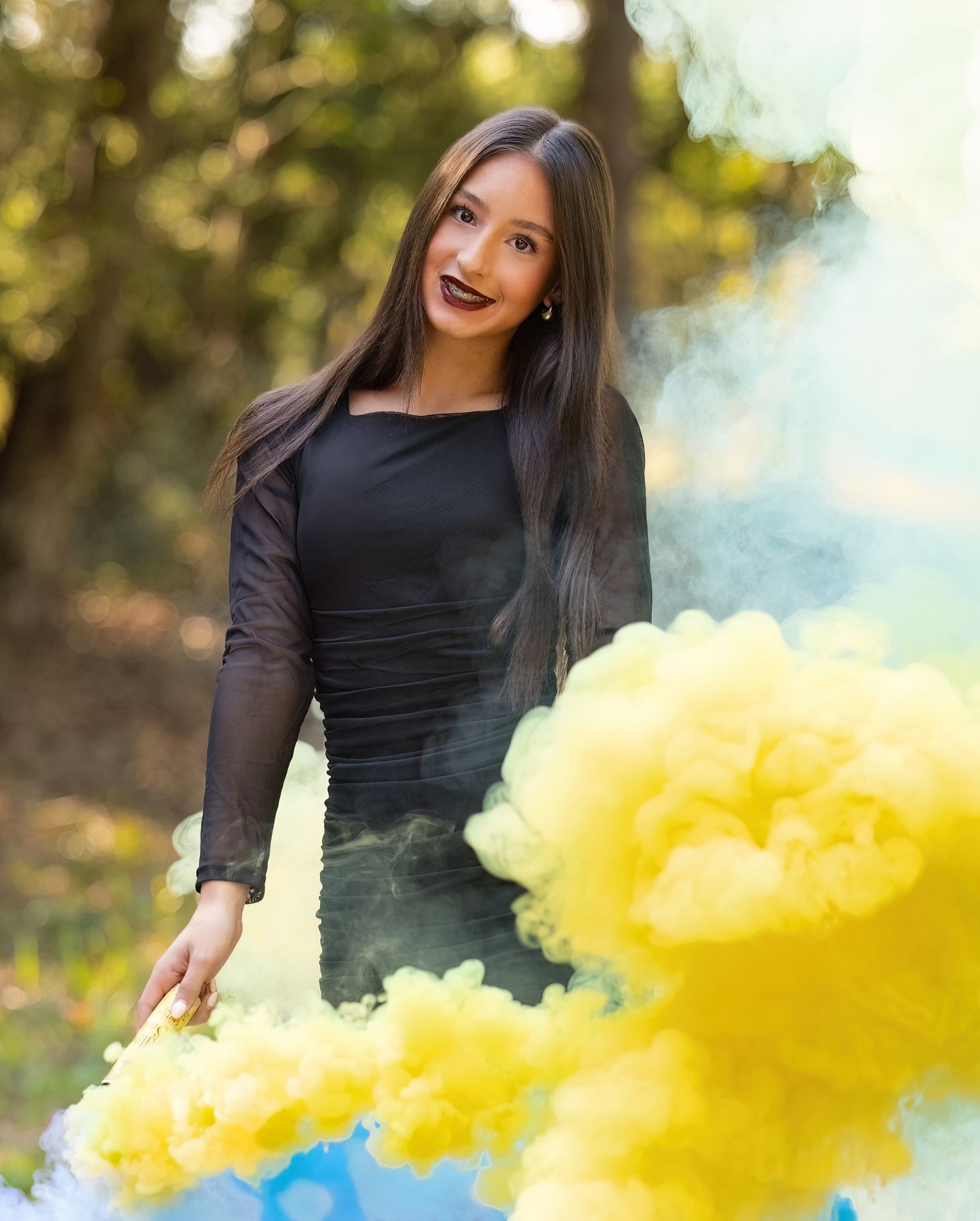 Artistic portrait session with bright yellow smoke effects against a natural outdoor backdrop.