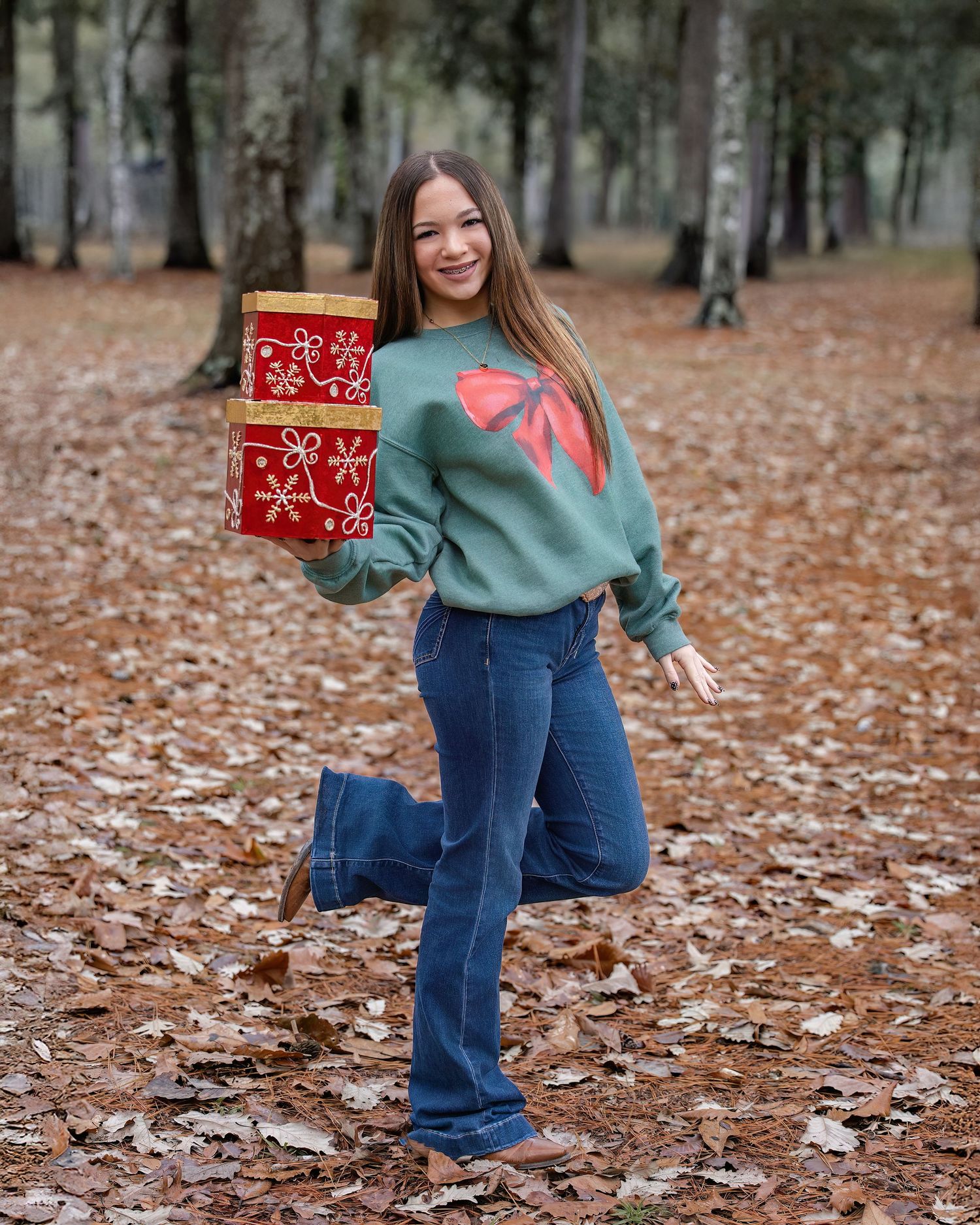 A person in a green sweater and flared jeans poses playfully in a park filled with autumn leaves.