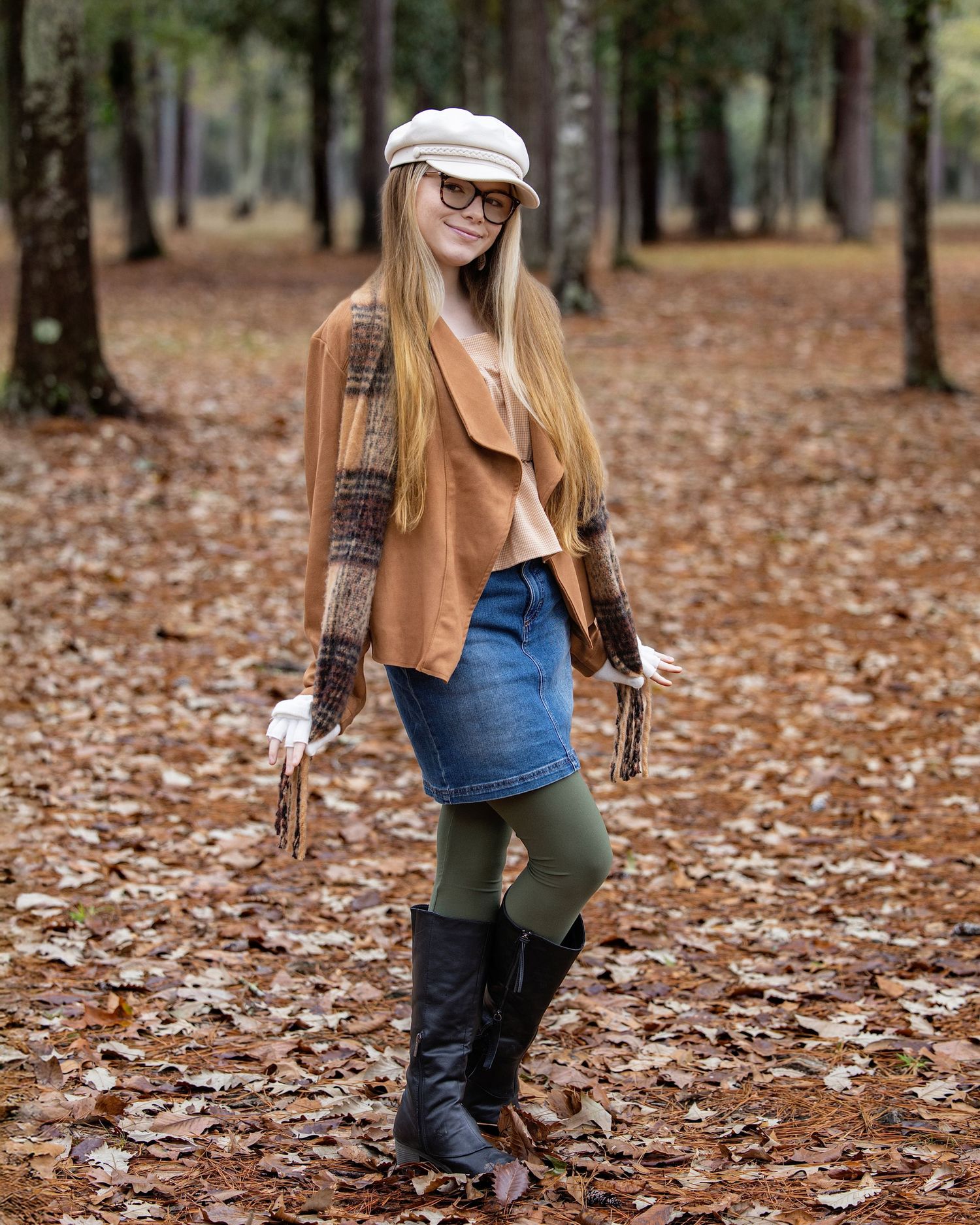 A casual autumn fashion shoot in a forest with fallen leaves showing layered outfits and boots.