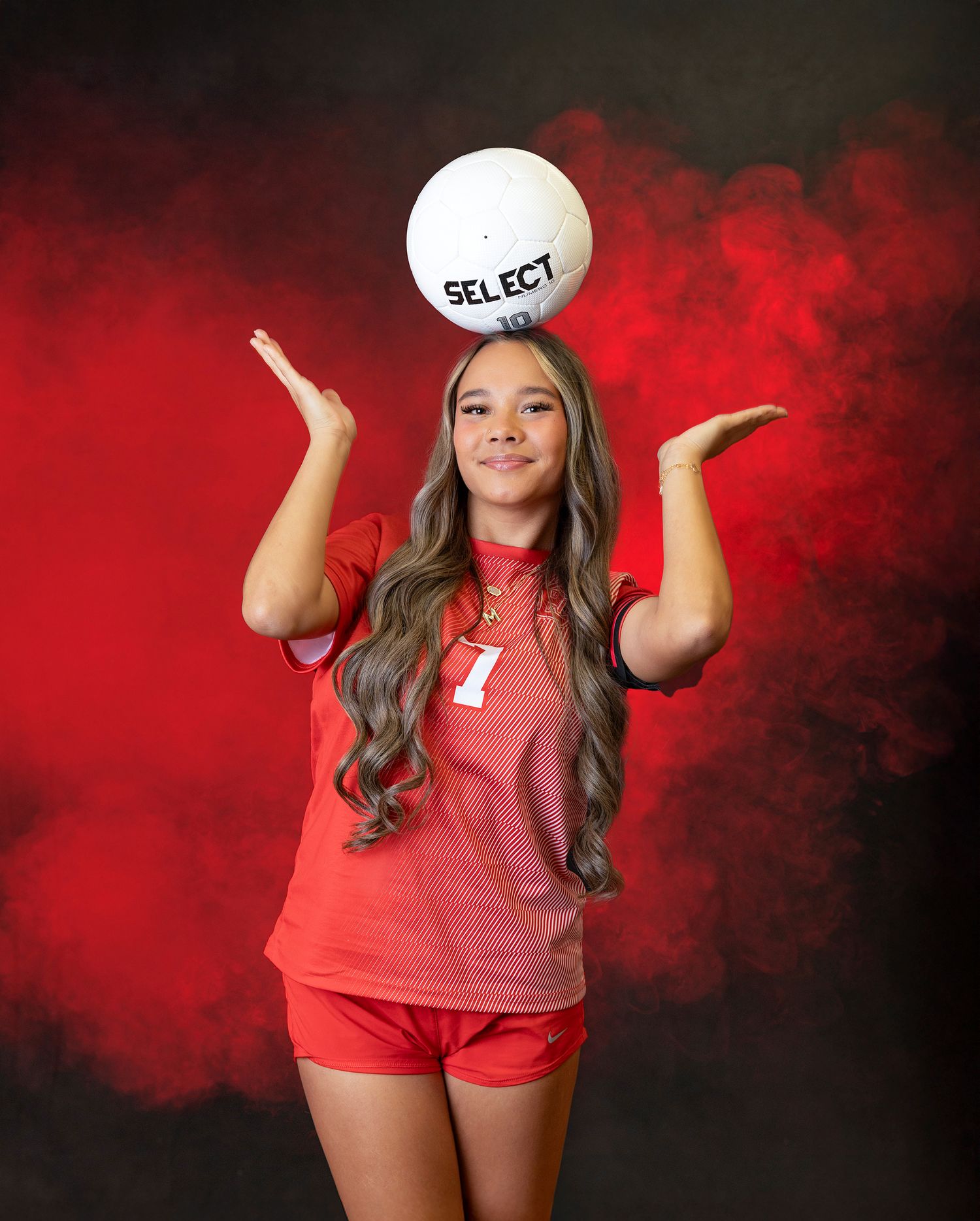 A volleyball player in red uniform poses with a ball against a dramatic red and black smoky background.