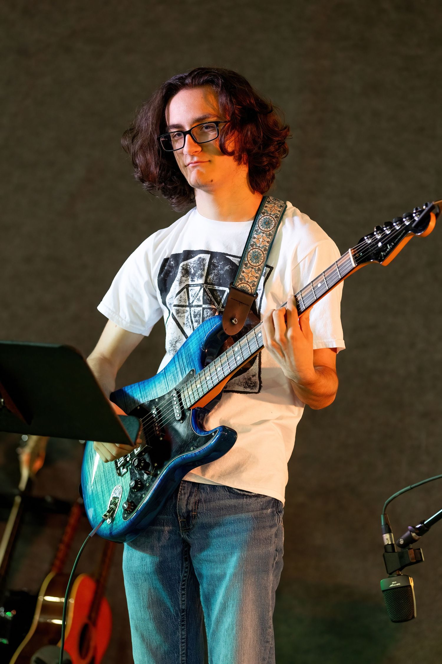 Concert Musician in glasses and white t-shirt playing electric guitar on stage in progressive sequence of performance shots.