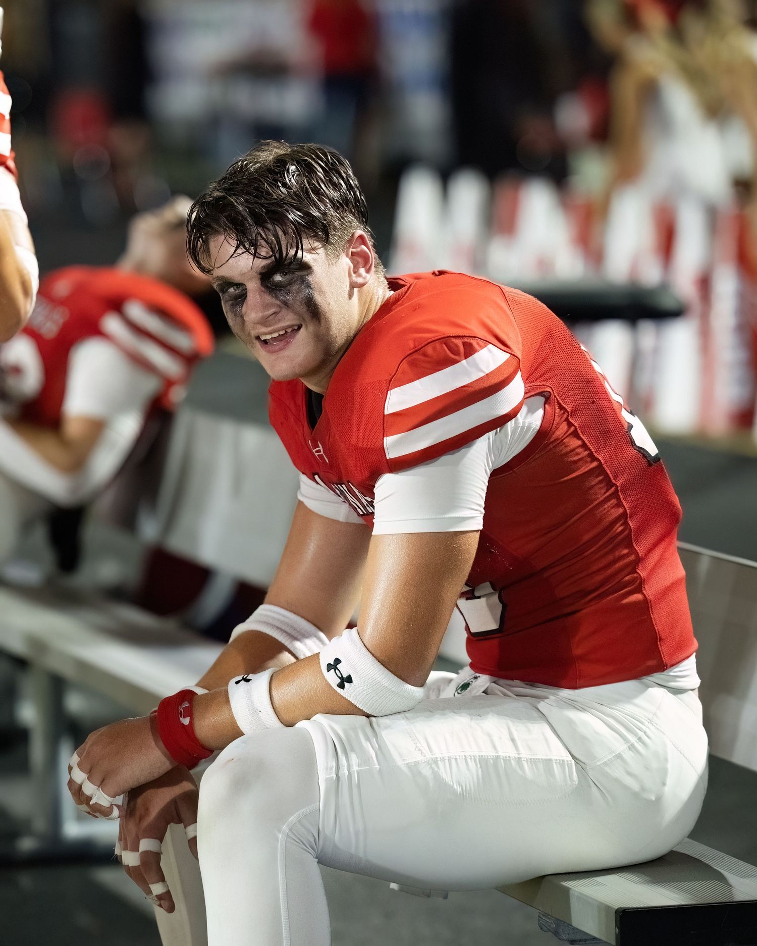 Bryce Breeden Bridge City Cardinal football players resting on the sideline bench during a game.