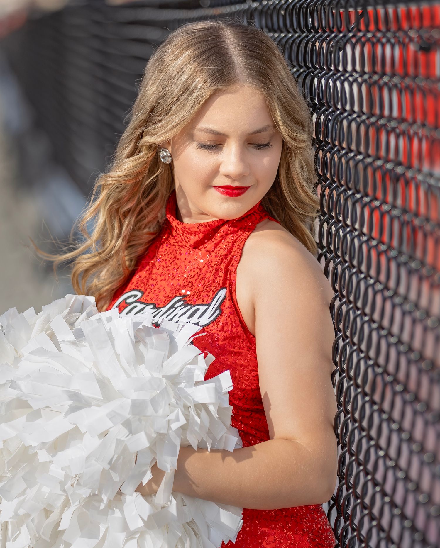 A figure in a sparkling red sequin dress with white tulle ruffles poses against a dark geometric background.