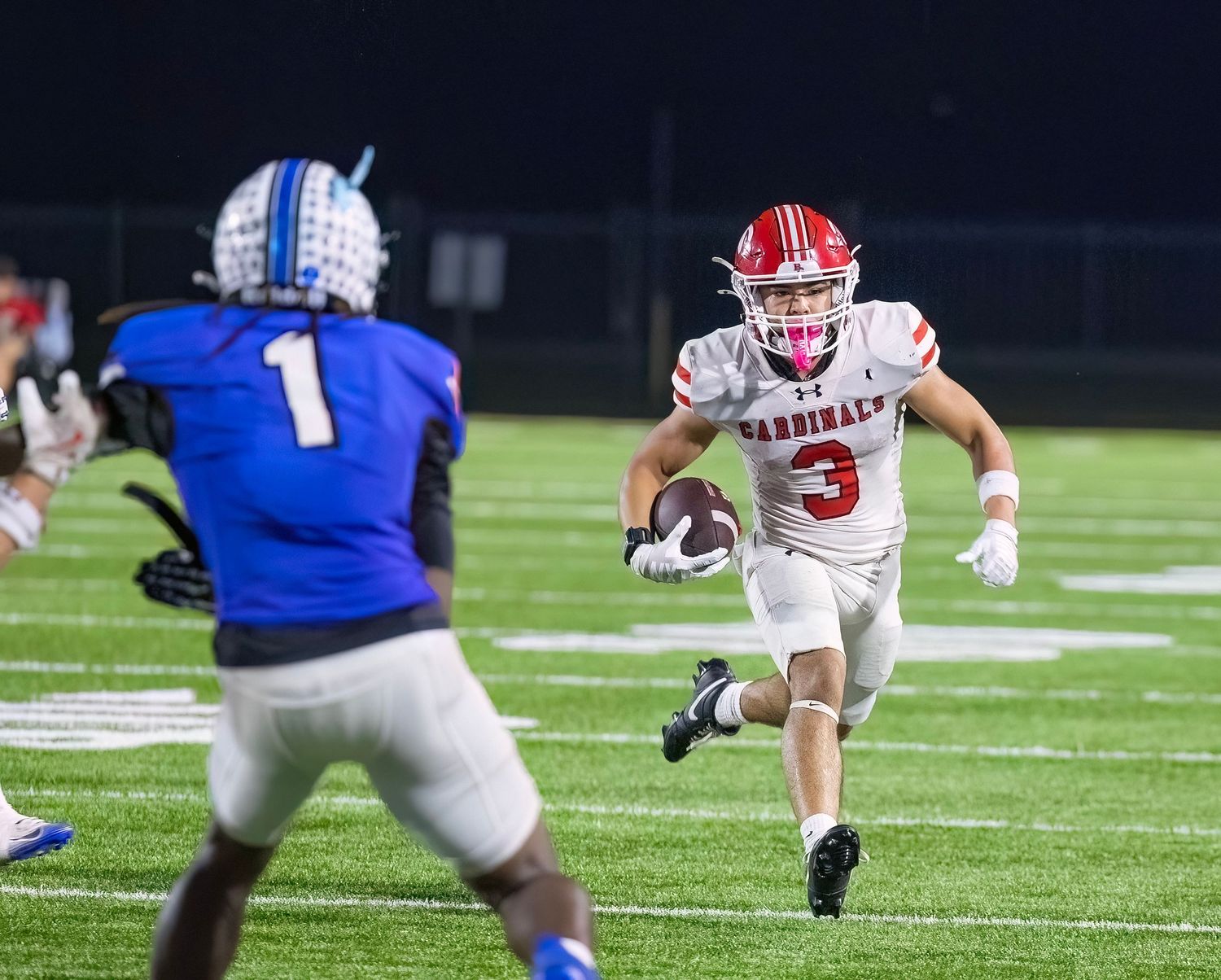 Football players from opposing teams compete for the ball on the field.
