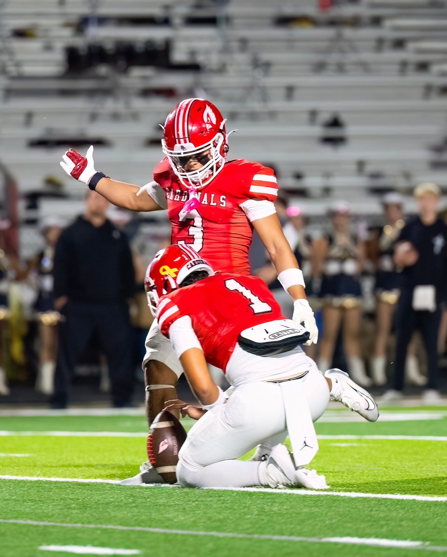 BC Football player in red uniform makes attemps field goal at stadium.