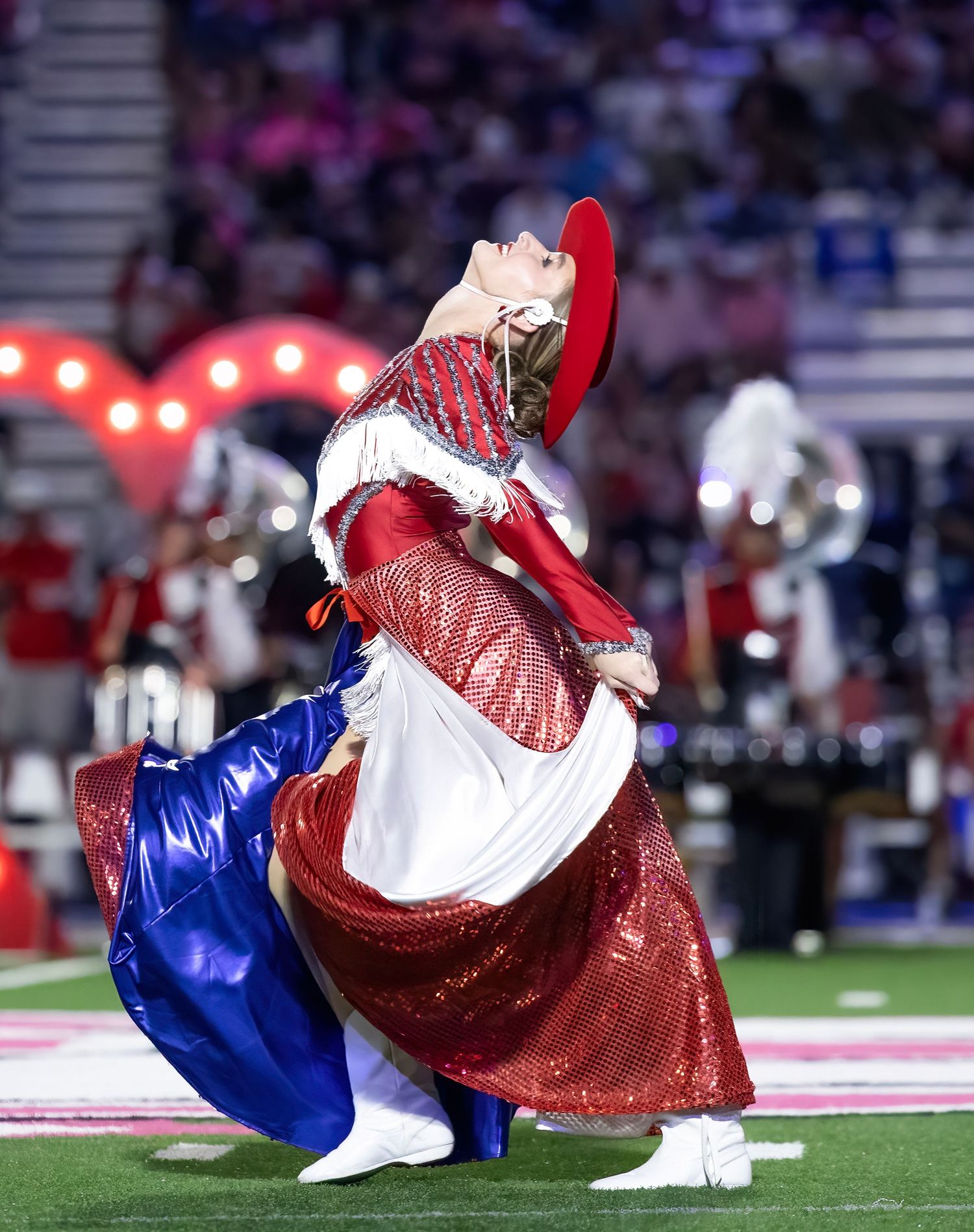 Performers execute a synchronized rolling movement in patriotic costumes during halftime show.