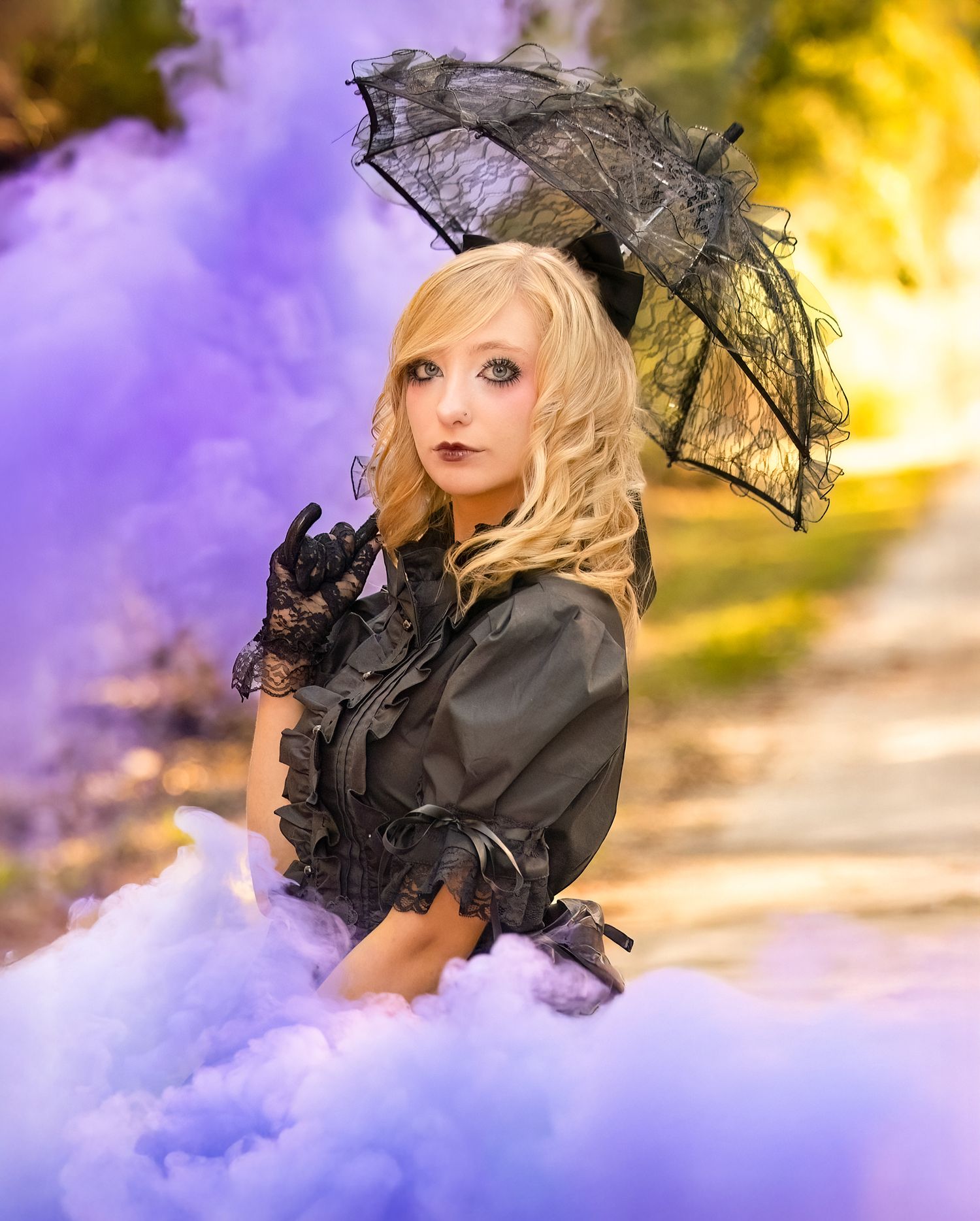 Fashion portrait with black lace parasol against purple and golden sunset backdrop.