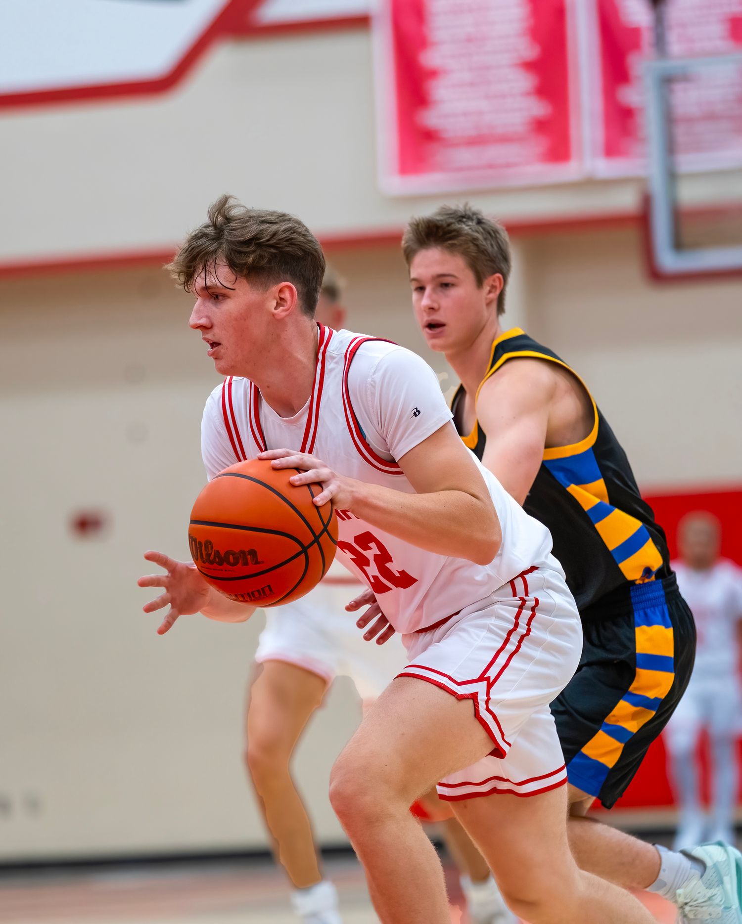 Basketball players from opposing teams battle for possession during a competitive high school game.