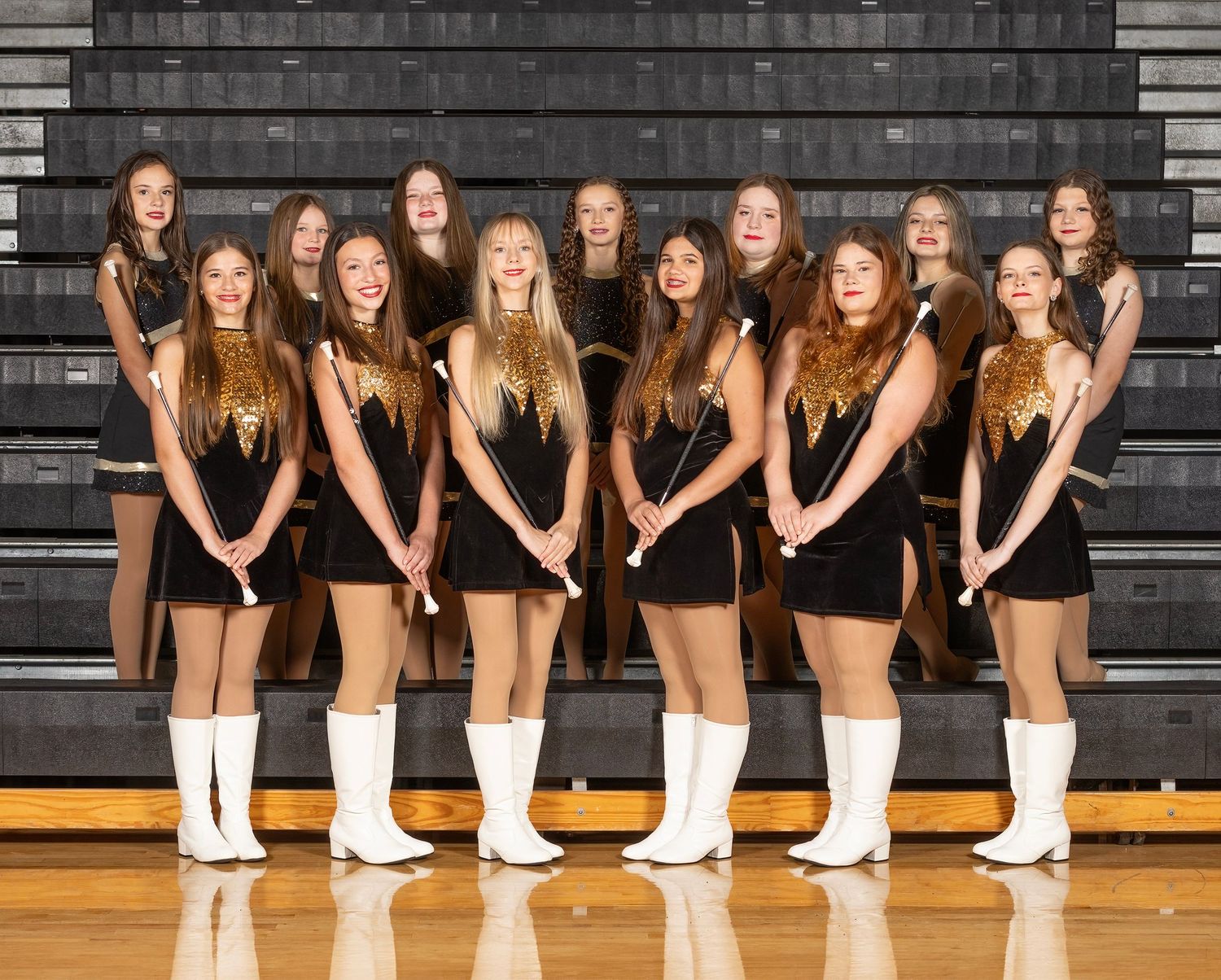 Dance team members pose in black outfits and white boots on bleachers for a creative panoramic photo.