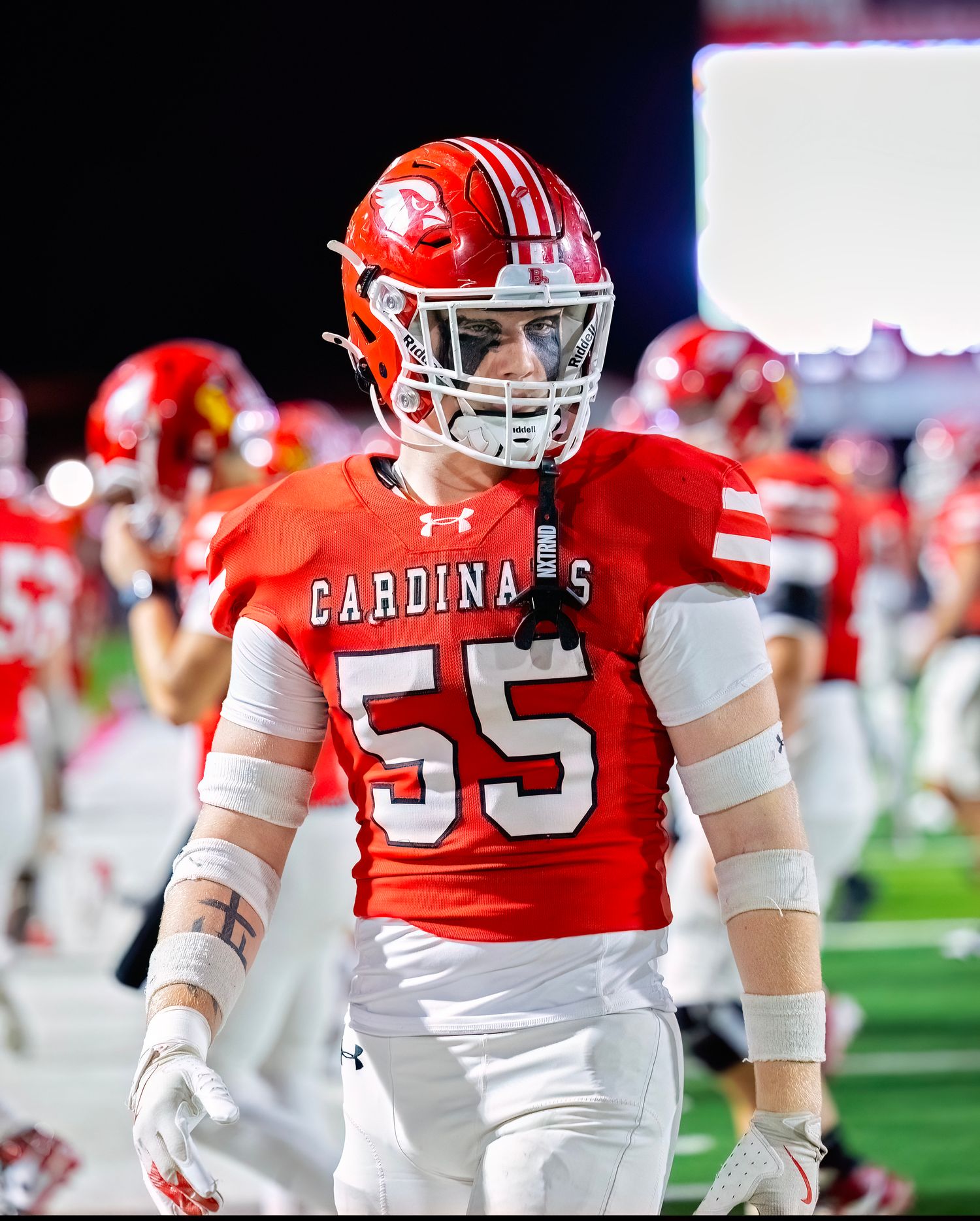 Football players in red Cardinals uniforms walking on the field during a game.