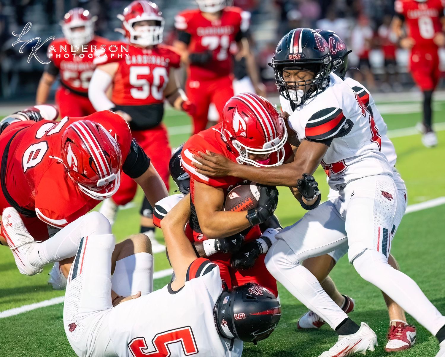 Football players from opposing teams collide during an intense tackle play on the field.
