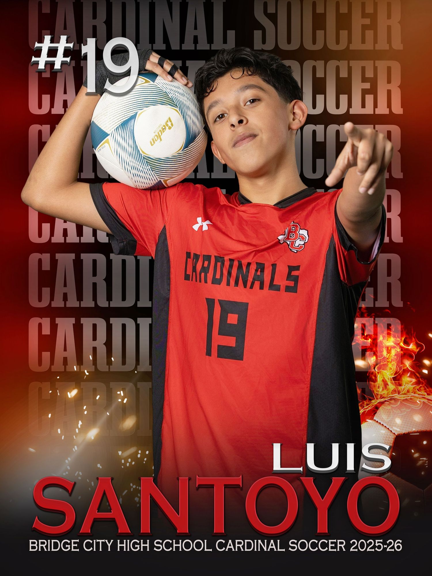 High school soccer player in red Cardinal uniform number 19 poses with soccer ball against dark backdrop.