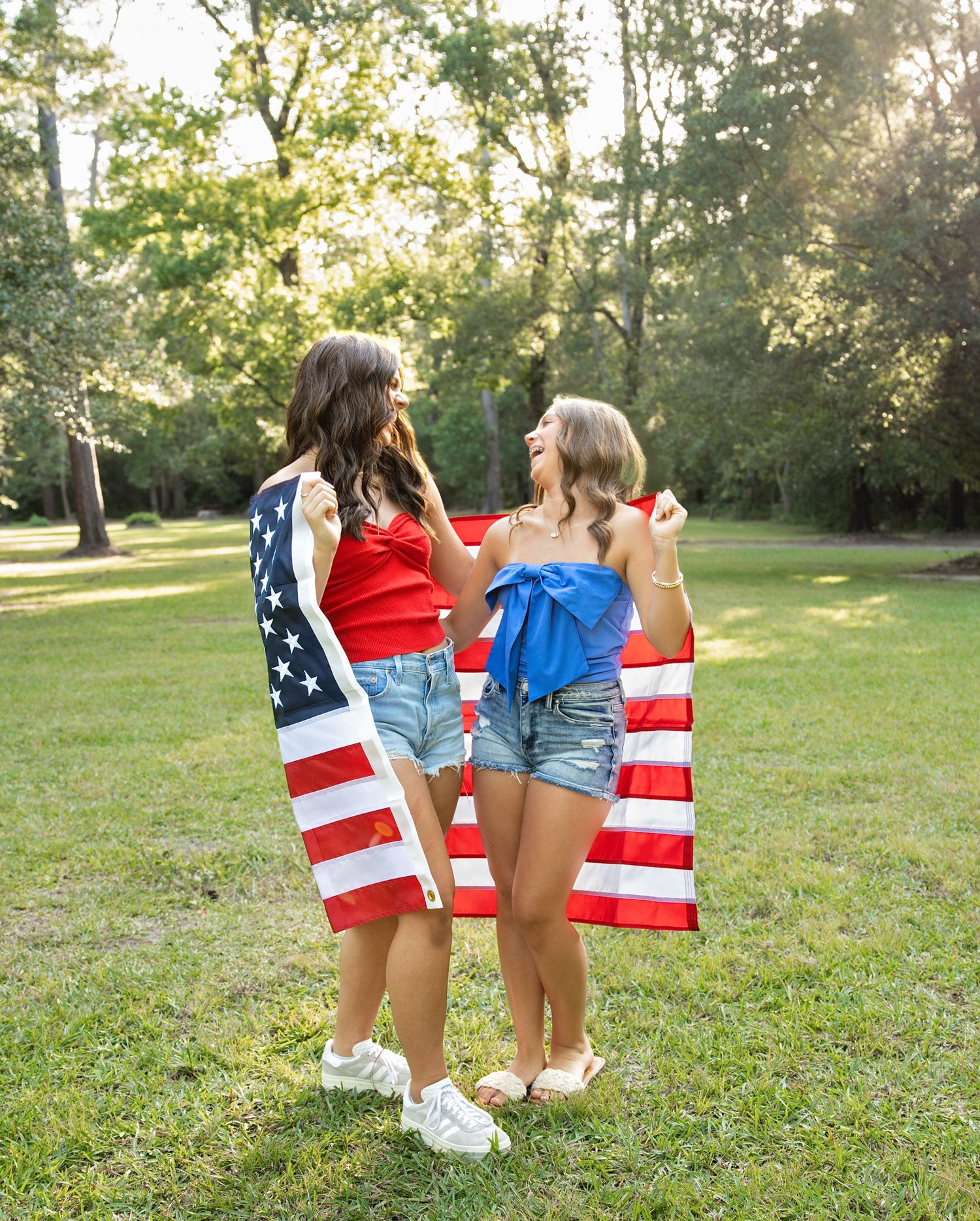 Two people holding an American flag in a sunny park during a patriotic outdoor photoshoot.
