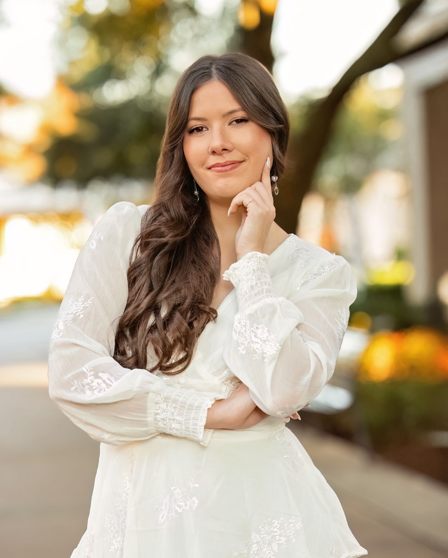 Lamar Senior in a white lace dress poses outdoors during golden hour with soft natural lighting.