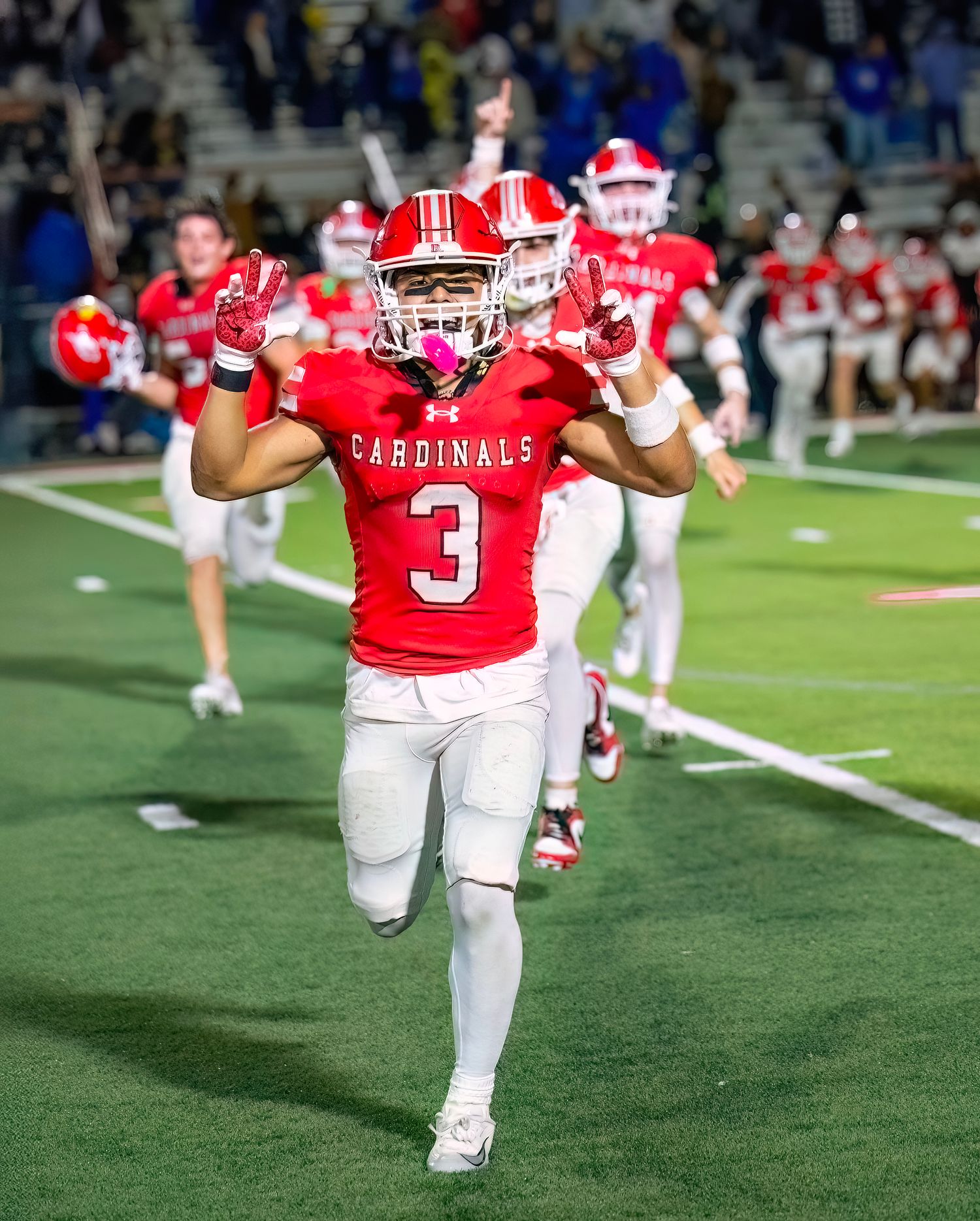 Cardinals football player in red jersey number 3 runs on field during game.