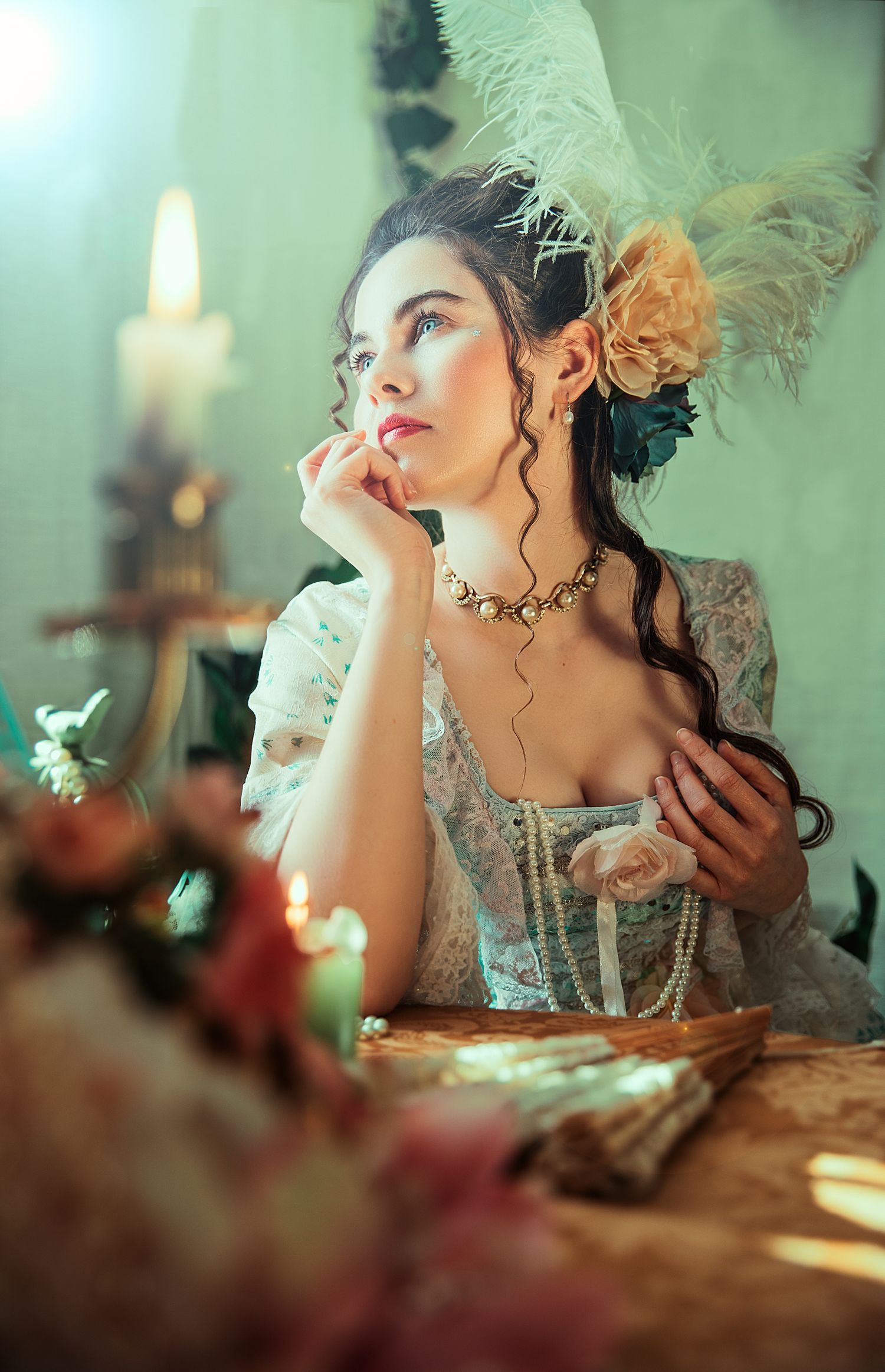 A woman in an ornate Victorian gown with floral headpiece sits pensively beside candles and flowers.