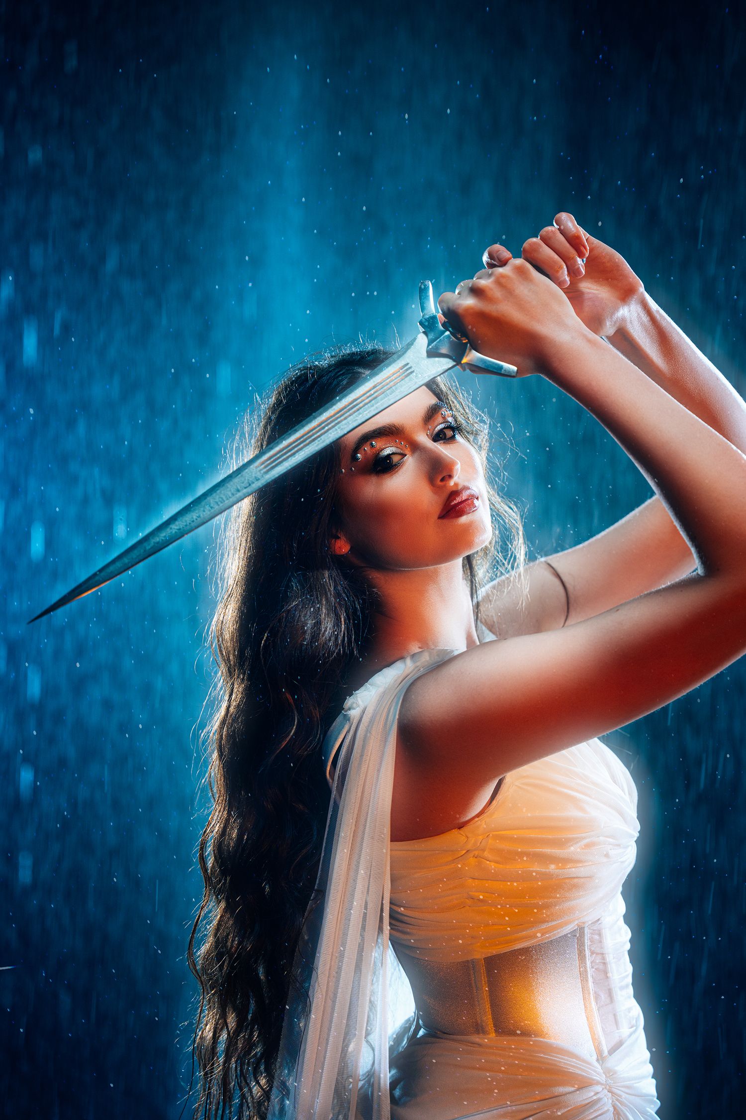 Dark-haired woman in white dress holding sword overhead in dramatic rain scene.