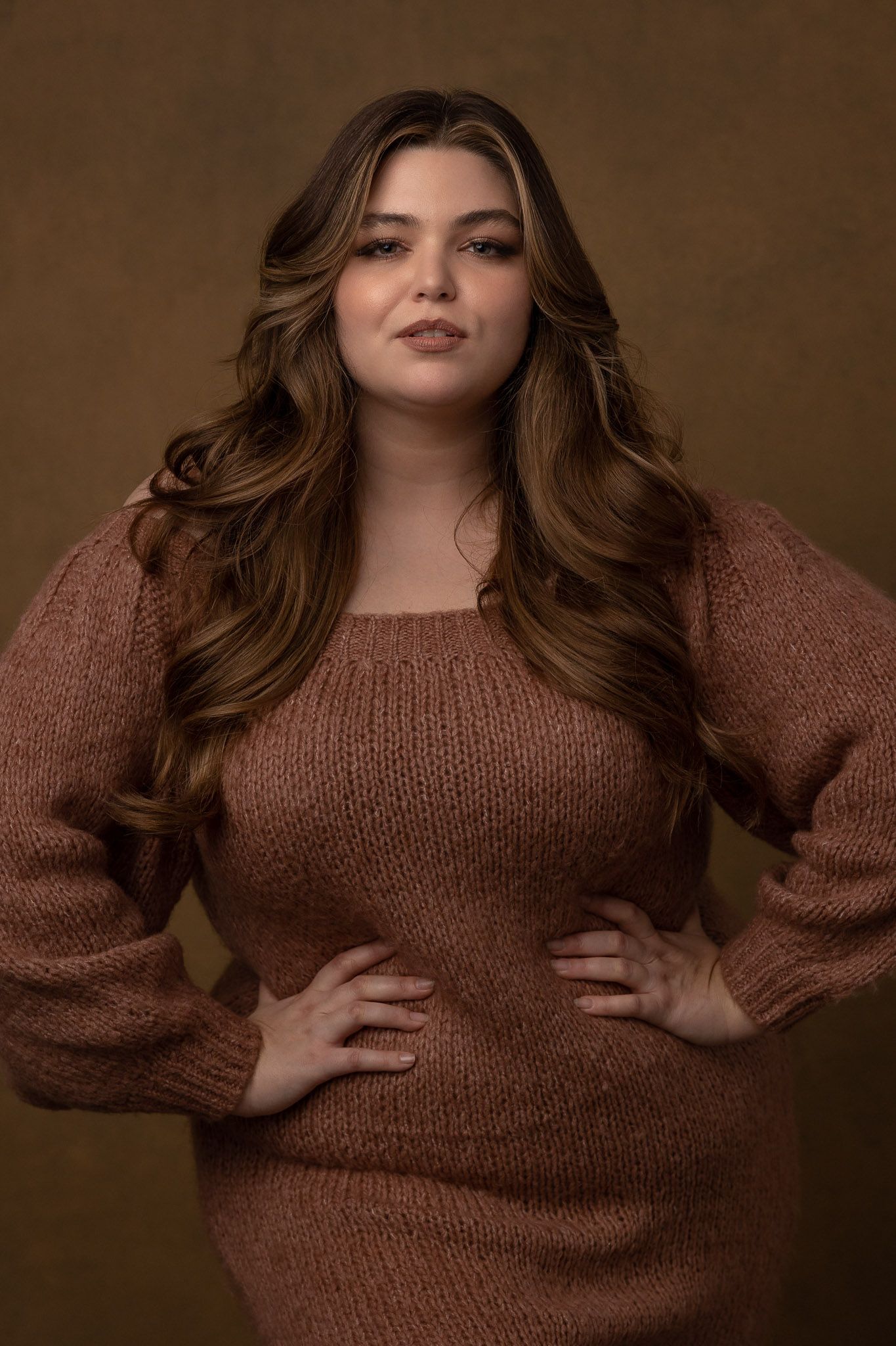 Fashion portrait series featuring brown knit sweater against warm brown backdrop.