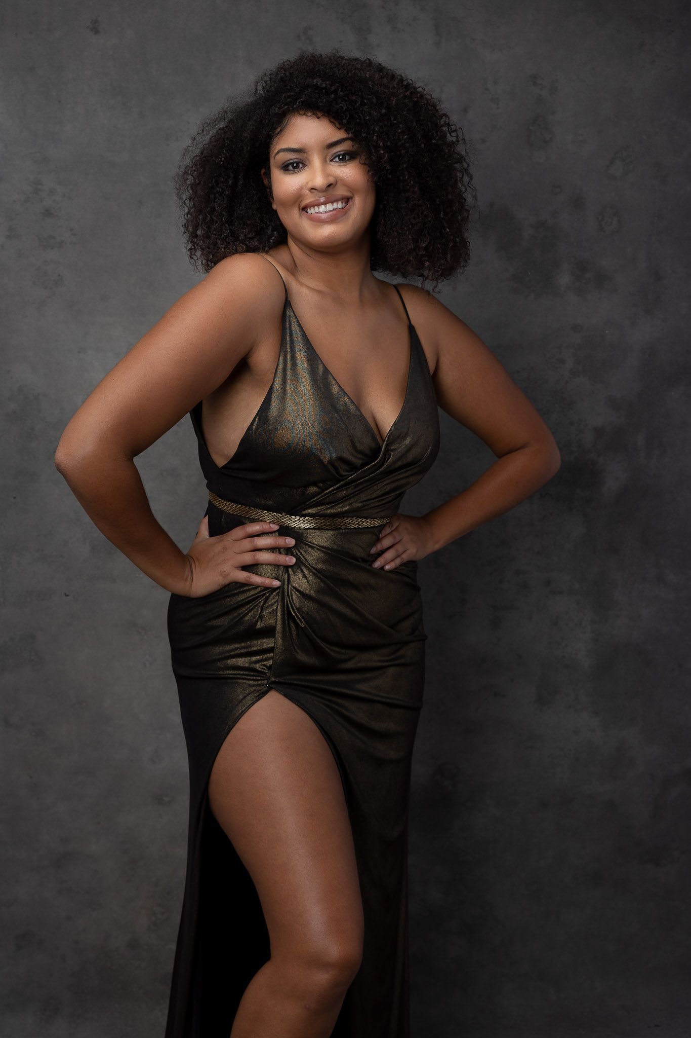Artistic boudoir photoshoot with olive satin dress against textured grey background.