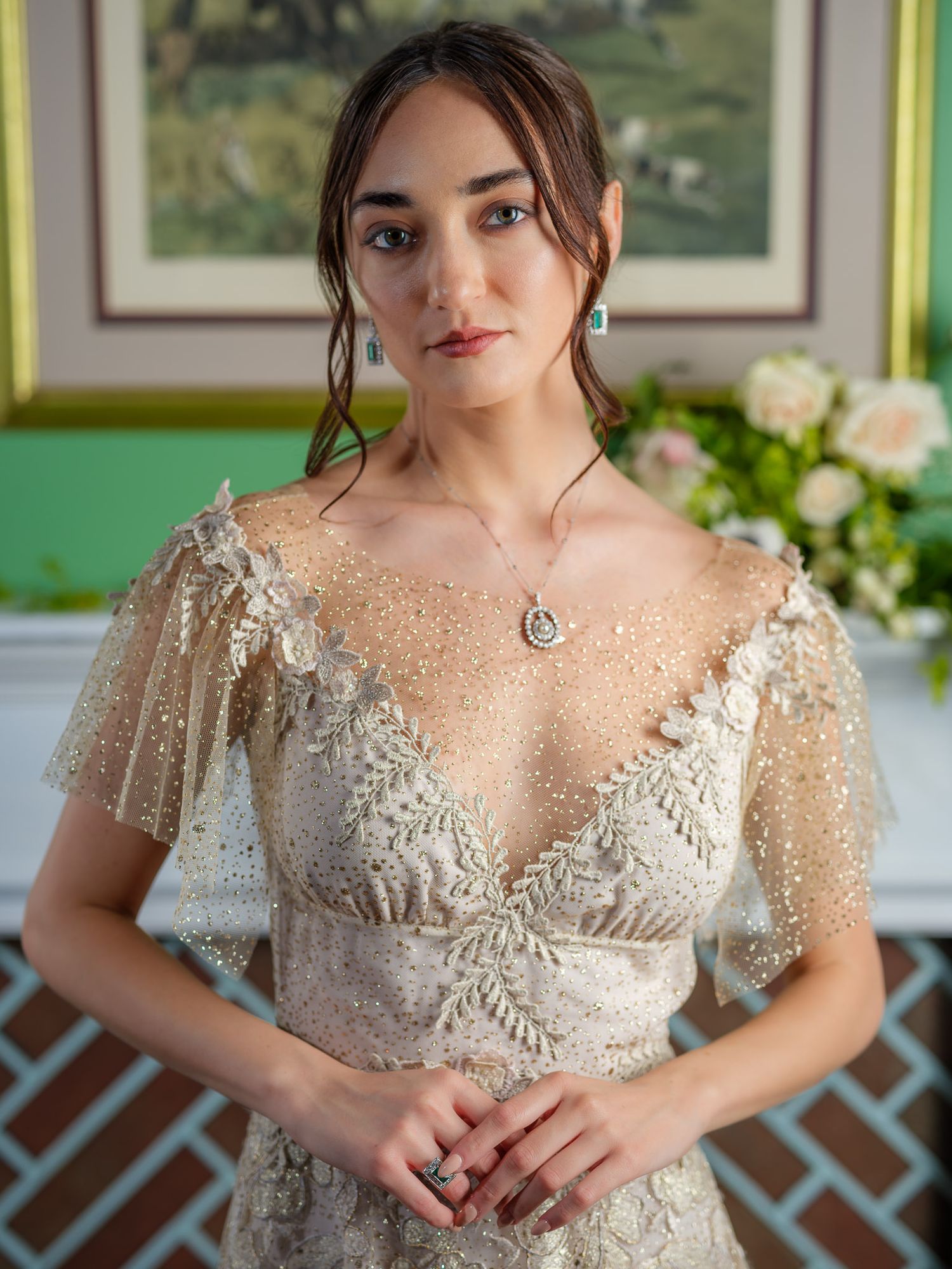 Delicate beaded lace details shine on an ethereal wedding gown in a bright indoor setting.