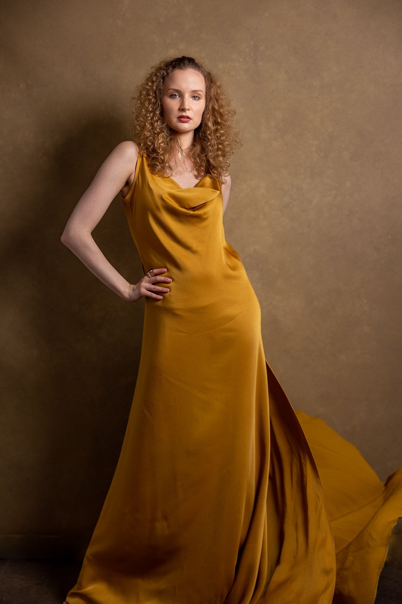 A golden velvet dress flows elegantly in a series of dramatic studio portraits.