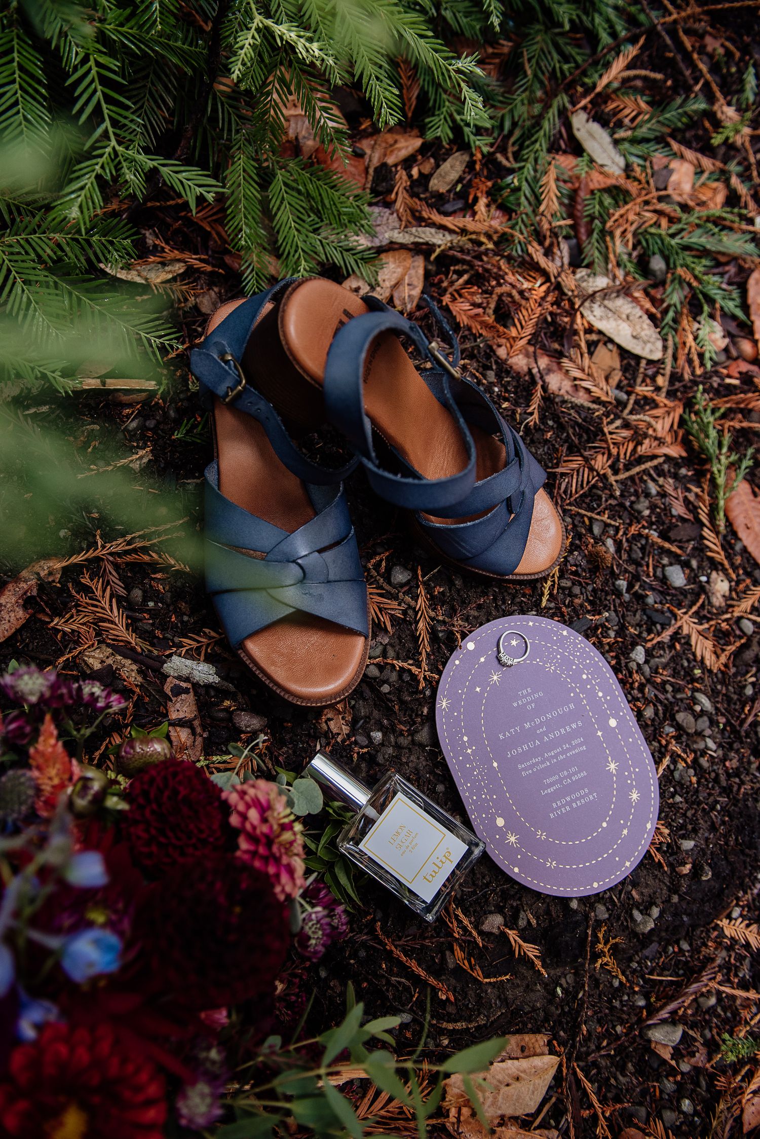 close up of wedding details, shoes, bouquet, wedding scent and invitation on the forest floor
