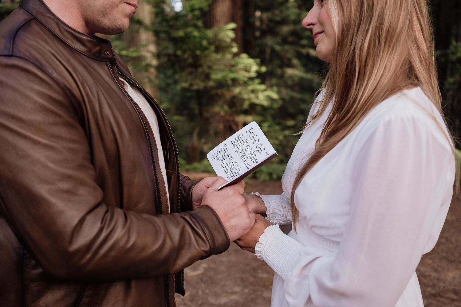 couple reading vows to each other, close up of their hands clasped