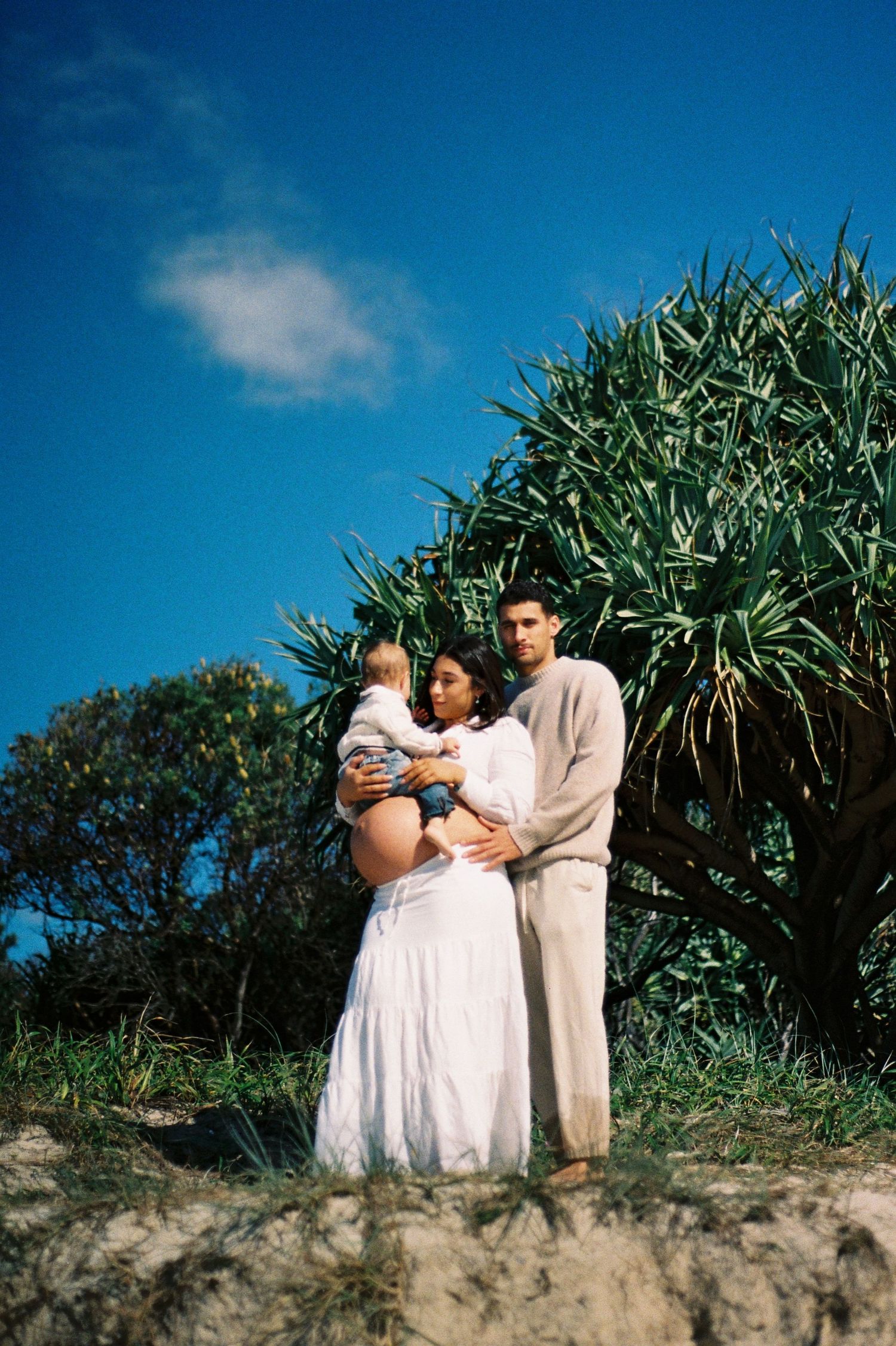 Parents holding their child at the beach.