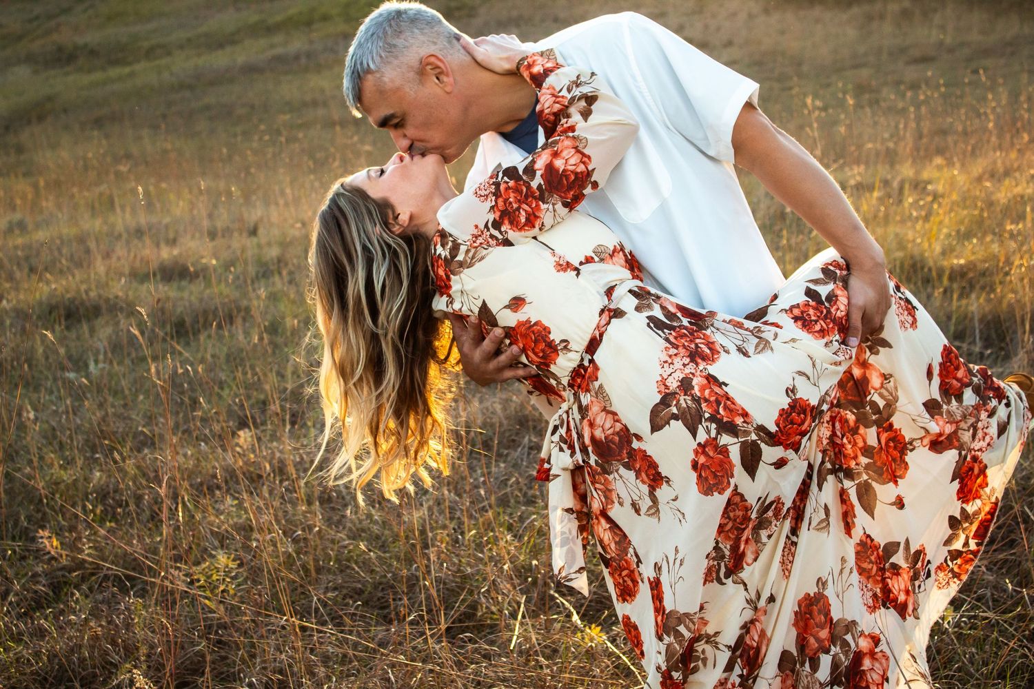 Person twirling in a floral dress against a sunset backdrop in a field.