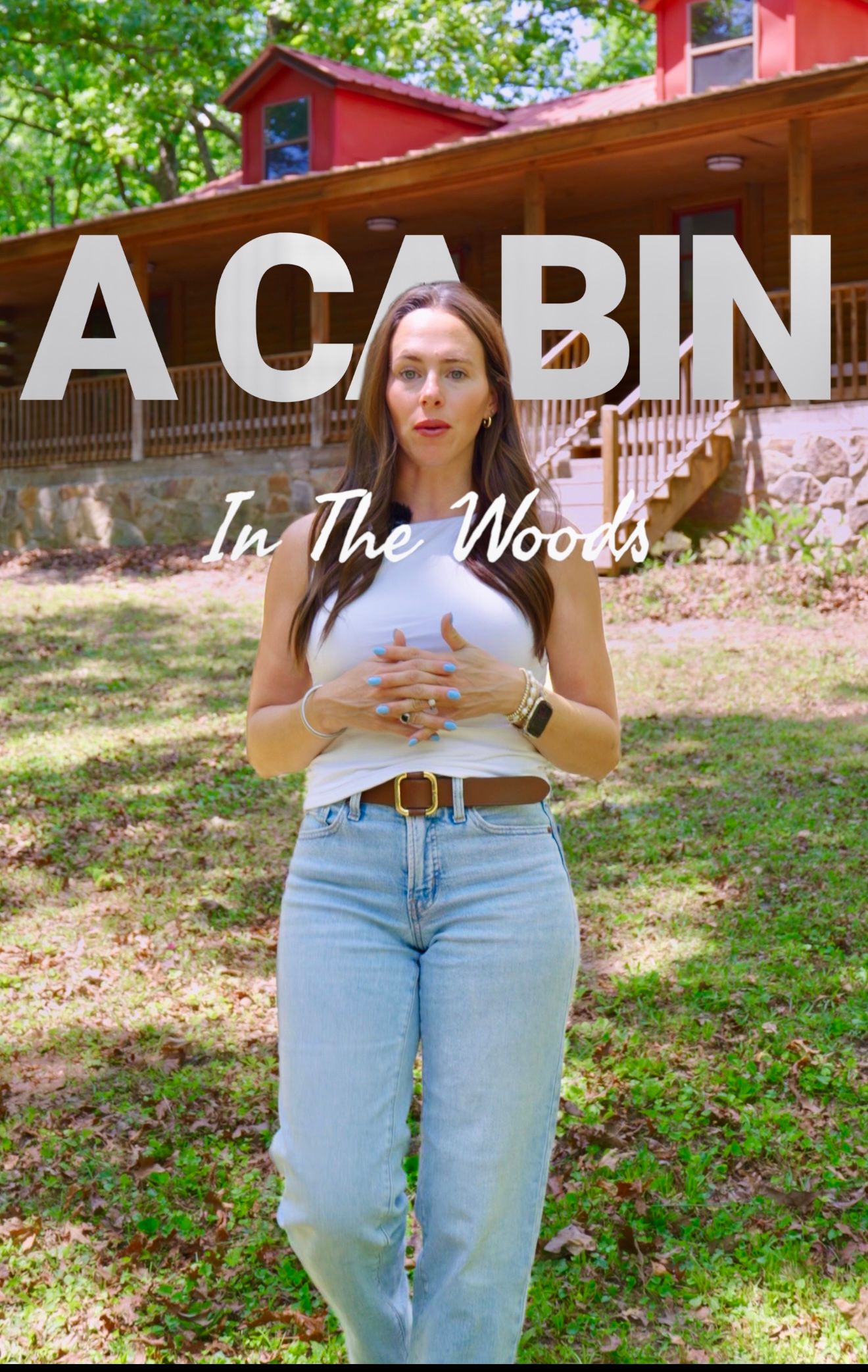 Woman standing outdoors in front of a red cabin in the woods, text overlay reads A Cabin In The Woods.