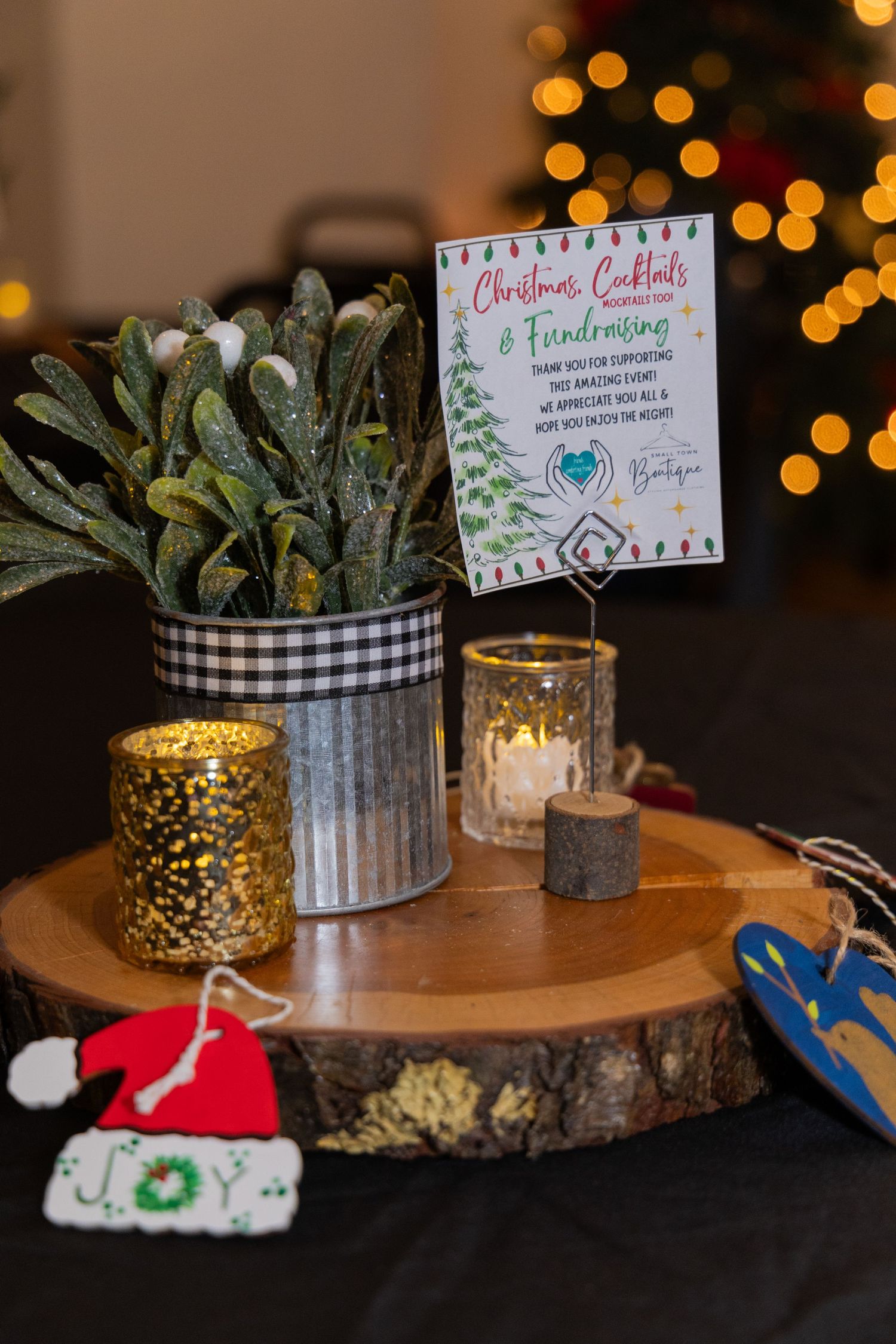 Decorative table settings with greenery and handwritten signs at a Christmas-themed event.
