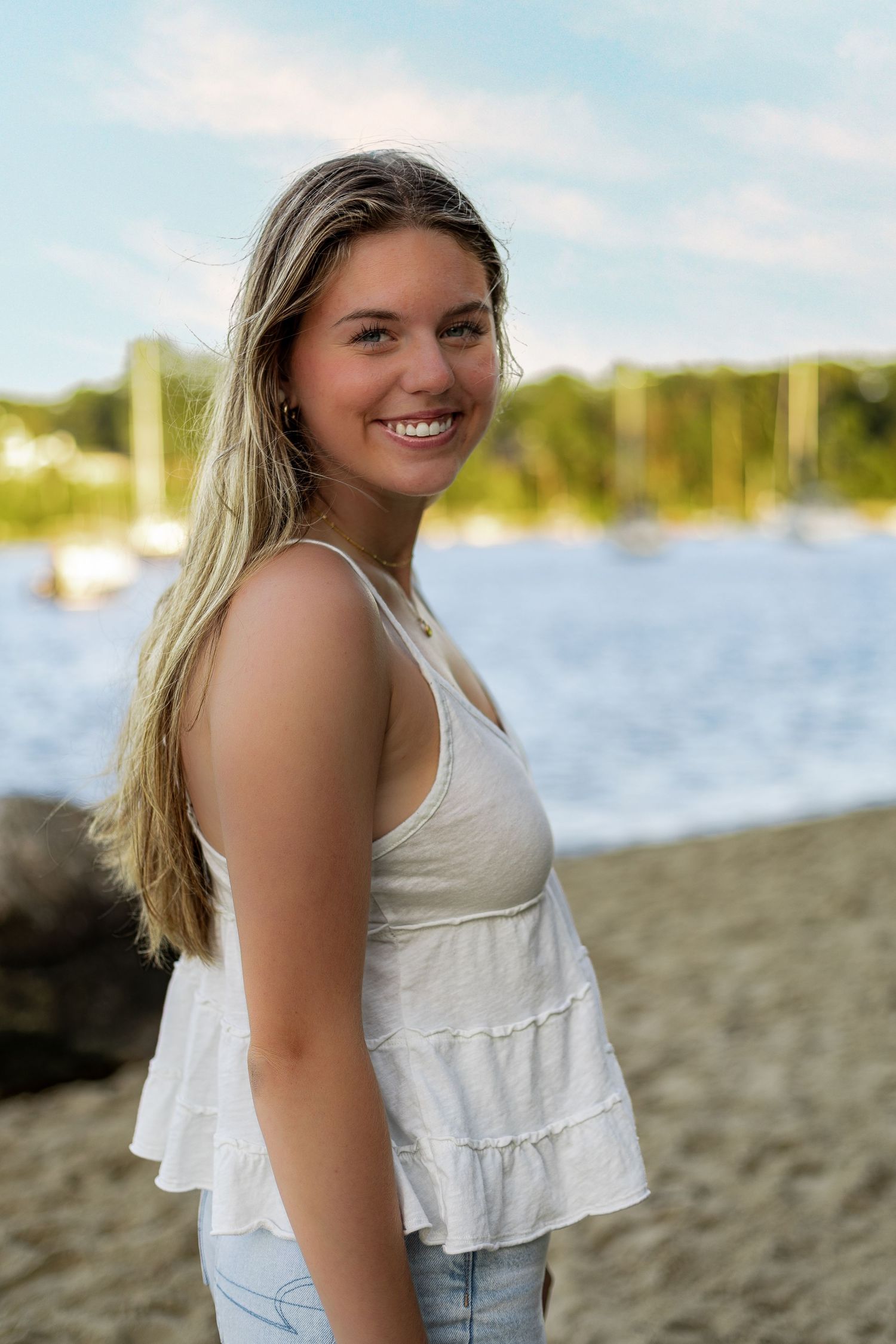 Beach portraits at sunset featuring casual summer attire near boats and water.